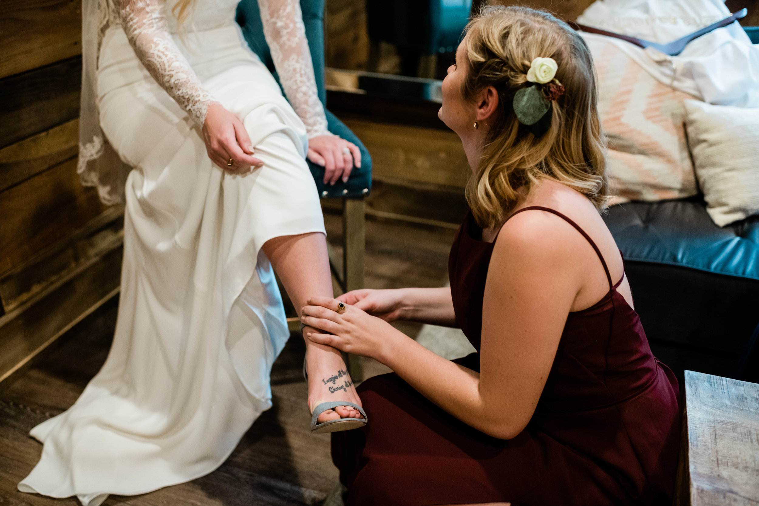 Bridesmaid helping put bride's shoe on