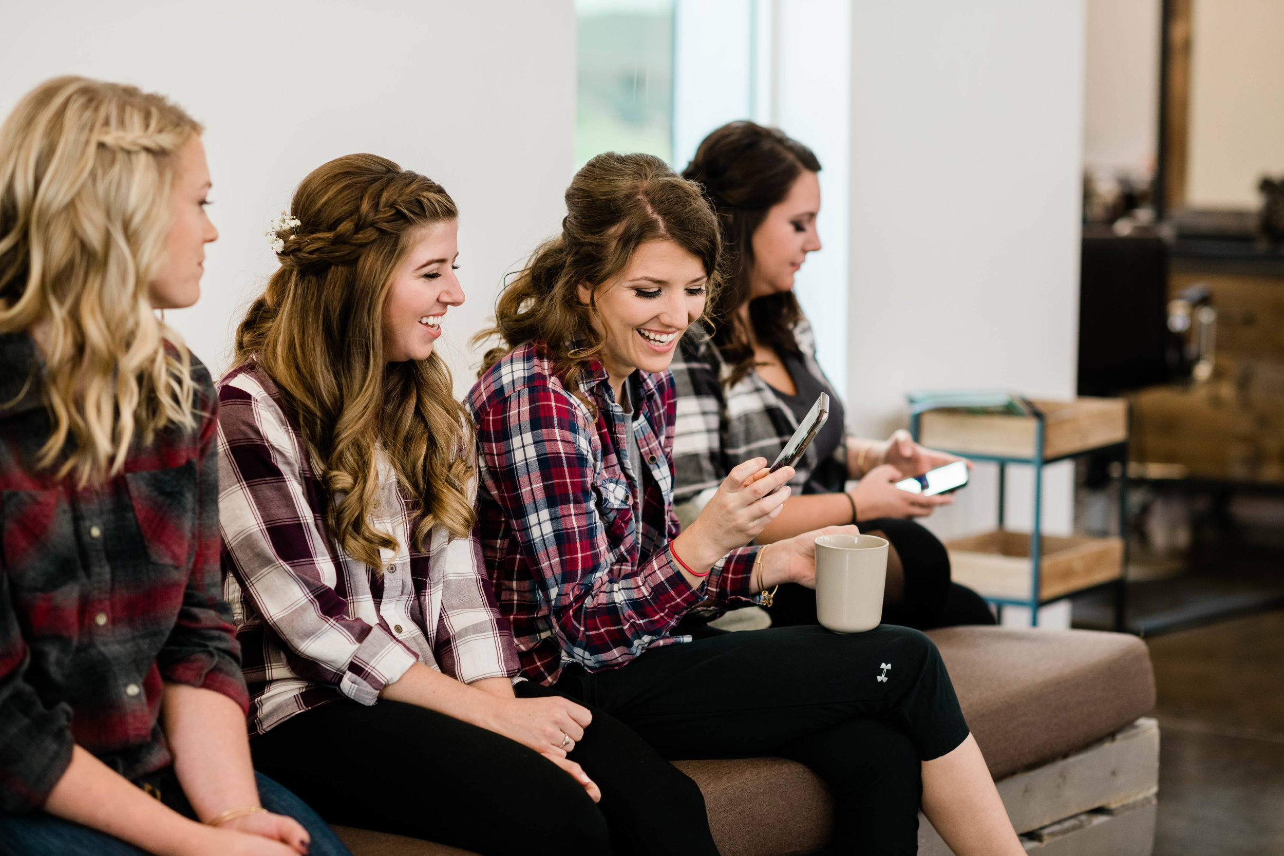 Bride and bridesmaids laughing at something on the phone