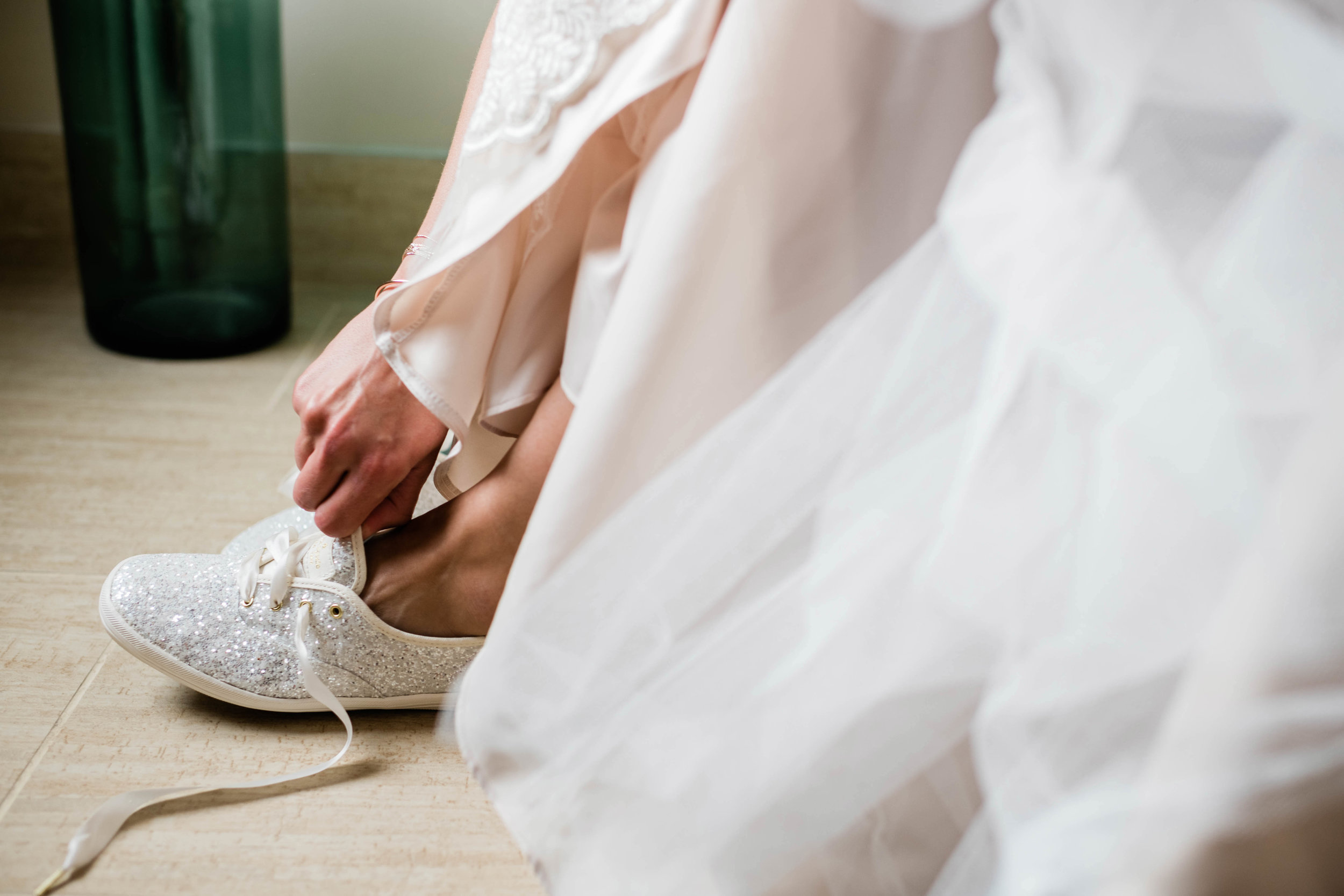 Bride putting on her glitter Keds shoes