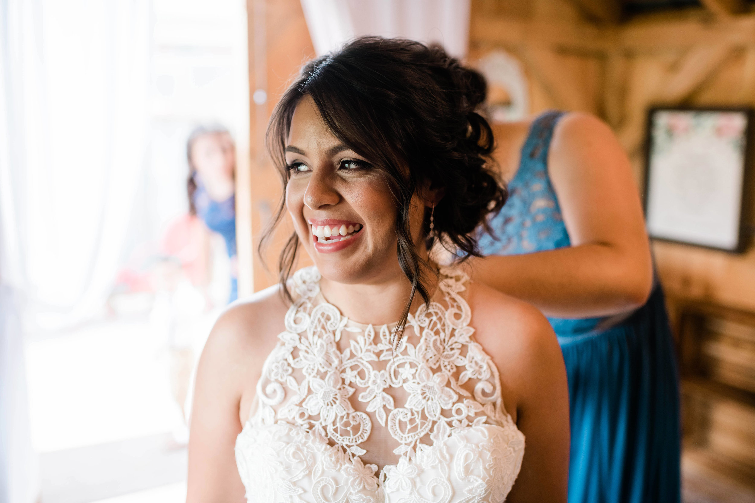 Bride smiles as her dress gets fastened