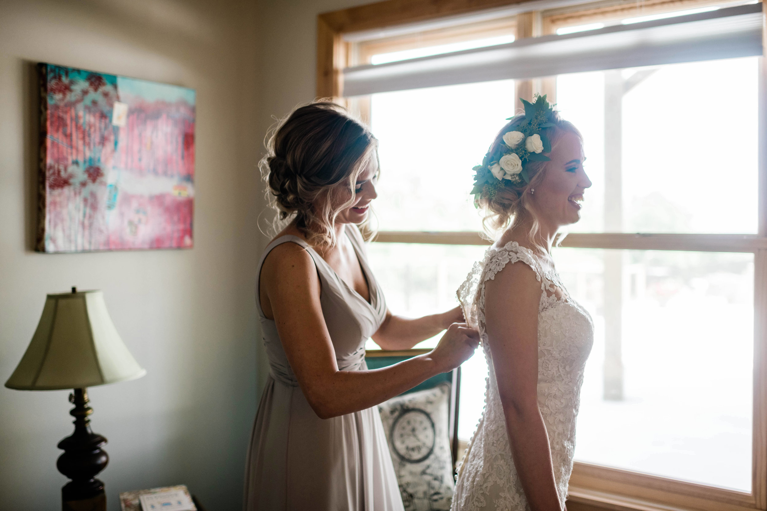 Bridesmaid helps bride with her dress