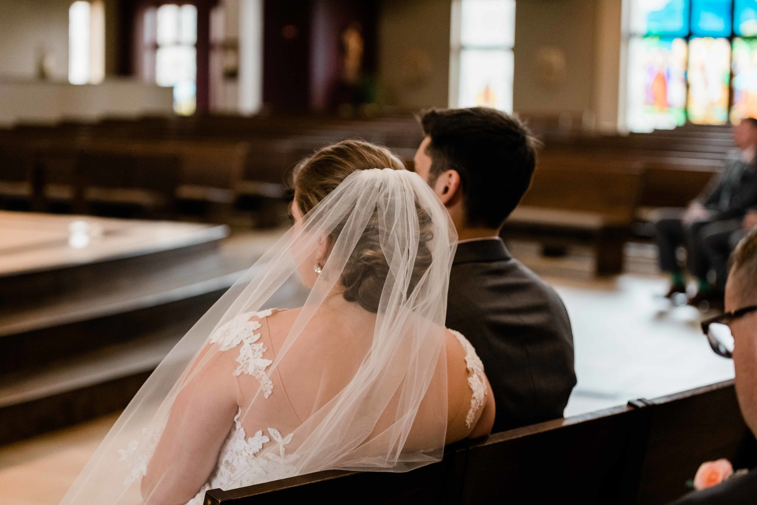 Bride and groom sit and listen to the priest at their wedding