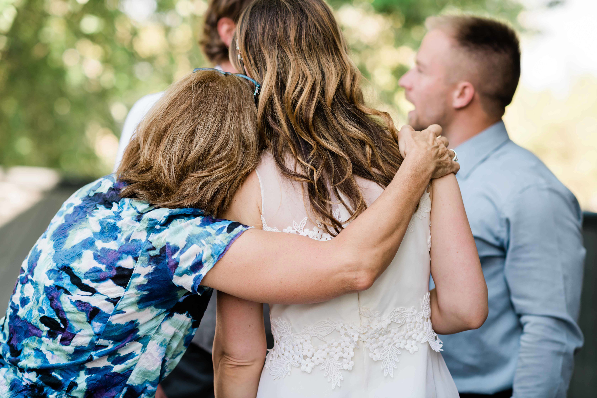 Wedding guest wraps her arm around the bride