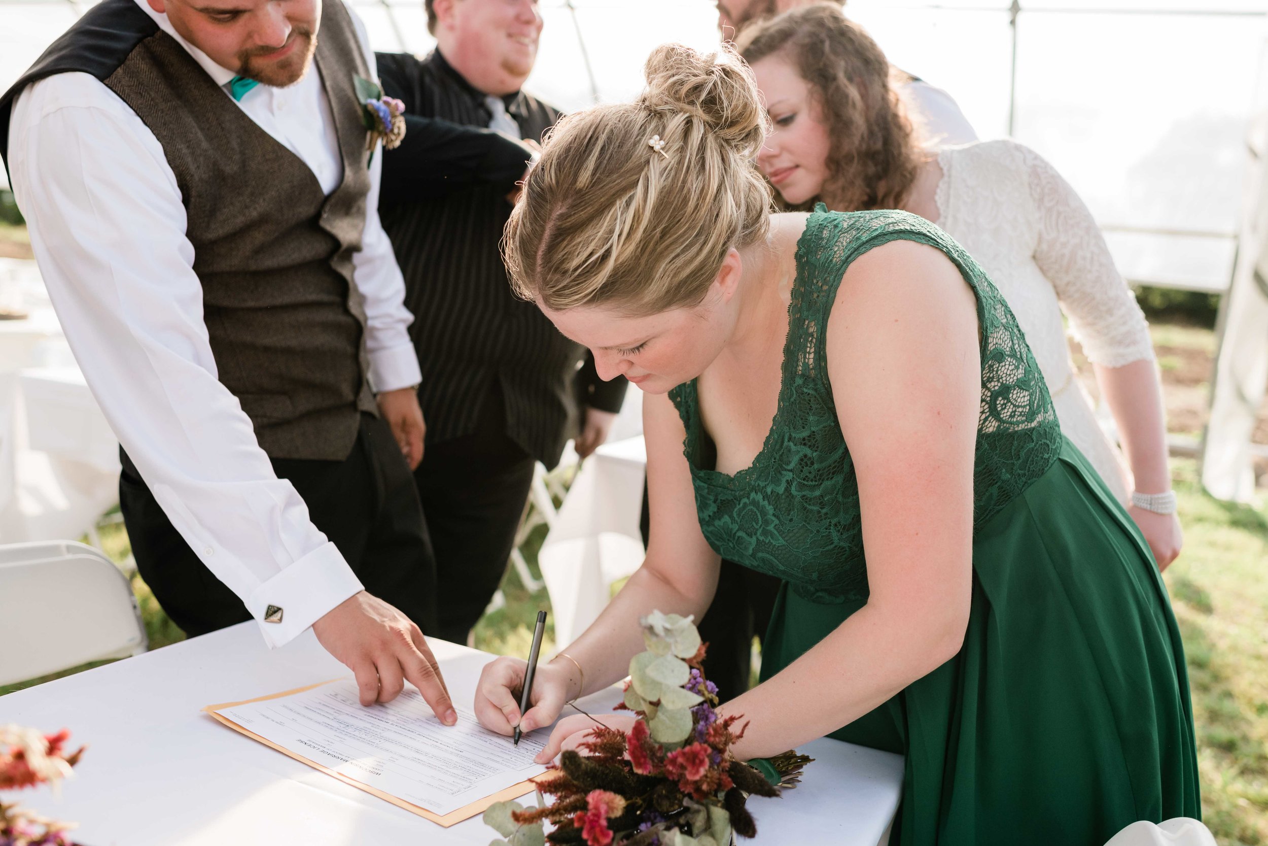 Bridesmaid signing as a witness on the marriage license