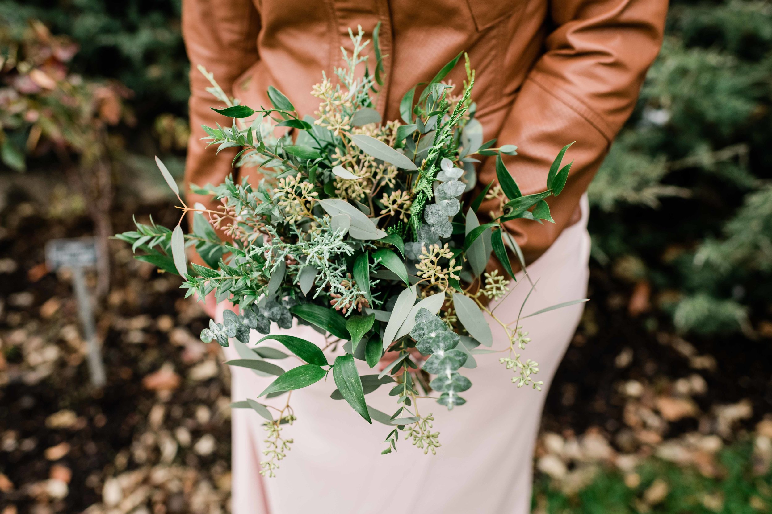 Bridesmaid in leather jacket holds bouquet