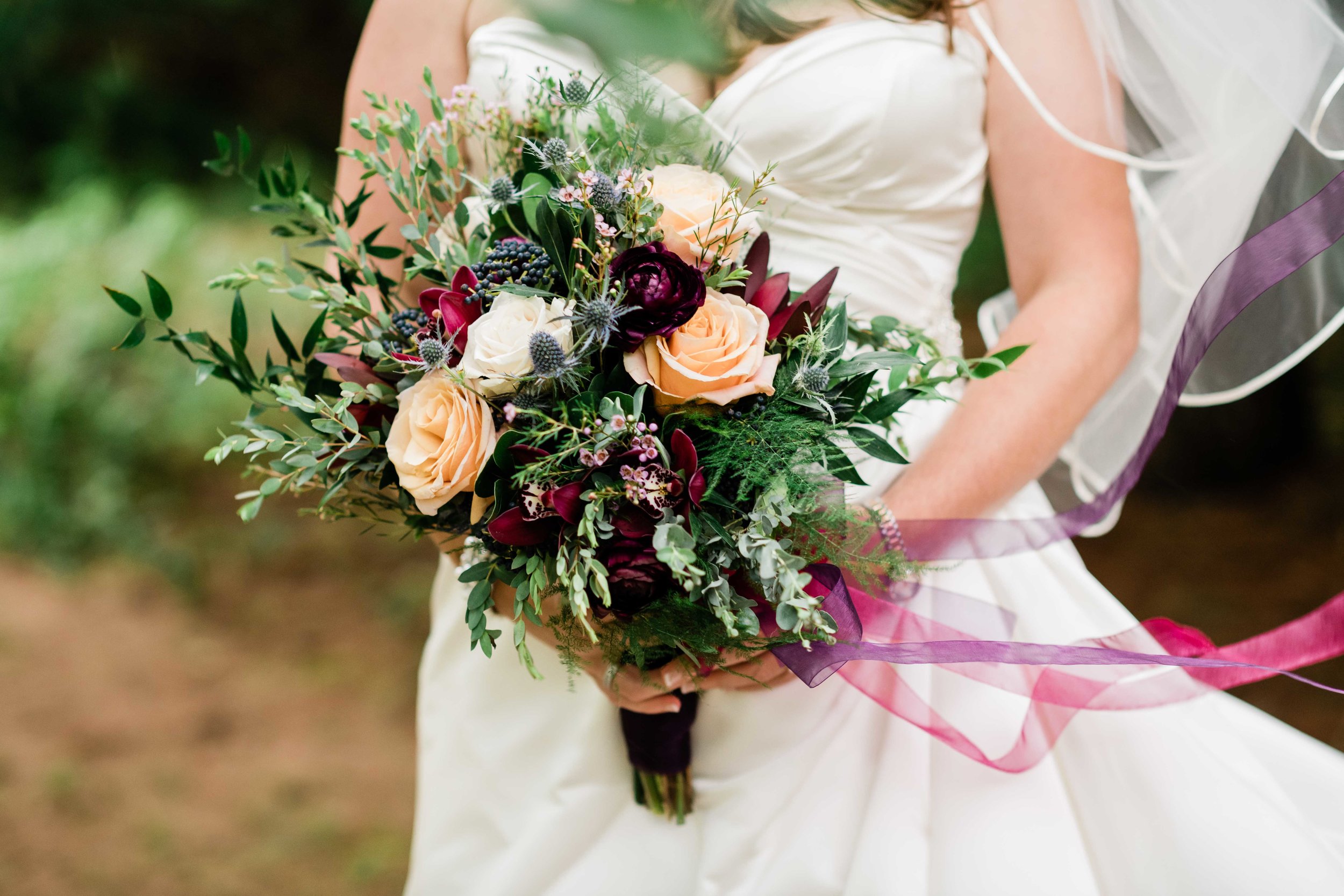 Bride's veil blows in the wind as she holds her bouquet