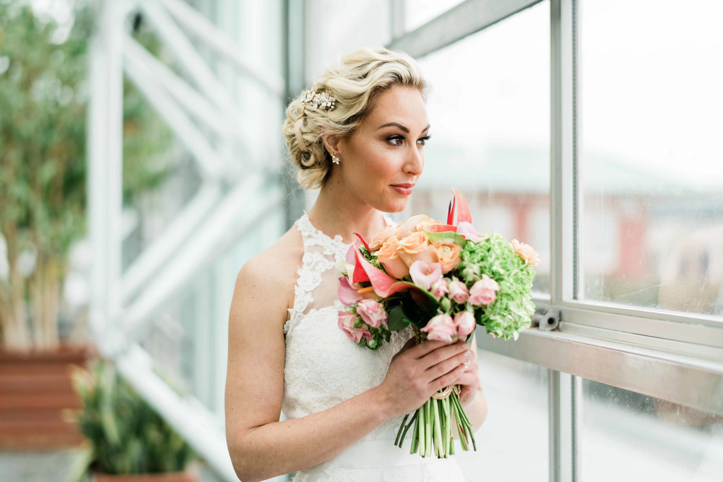 Bride looking out window with her bouquet