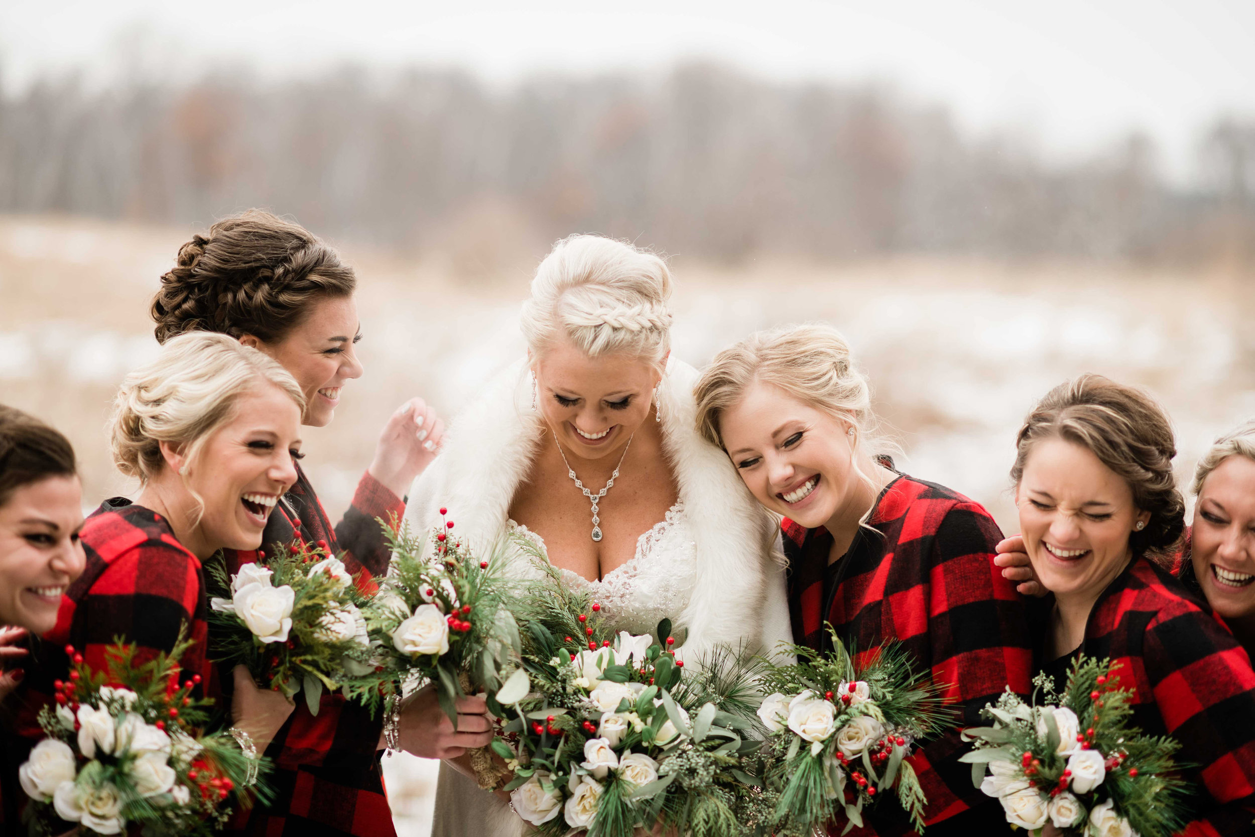 Bride and bridesmaids laughing as they huddle for warmth