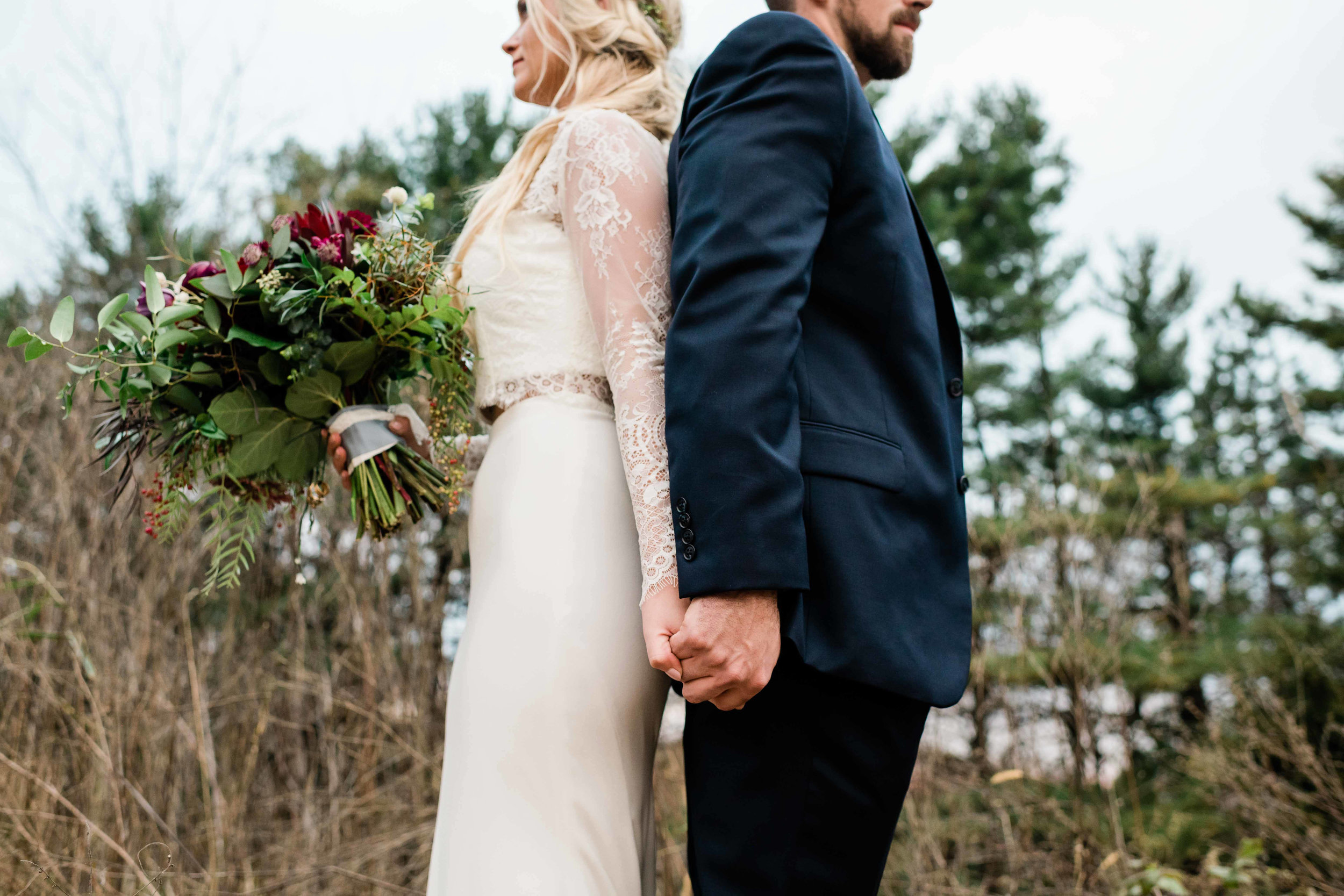 Bride and groom back to back holding hands