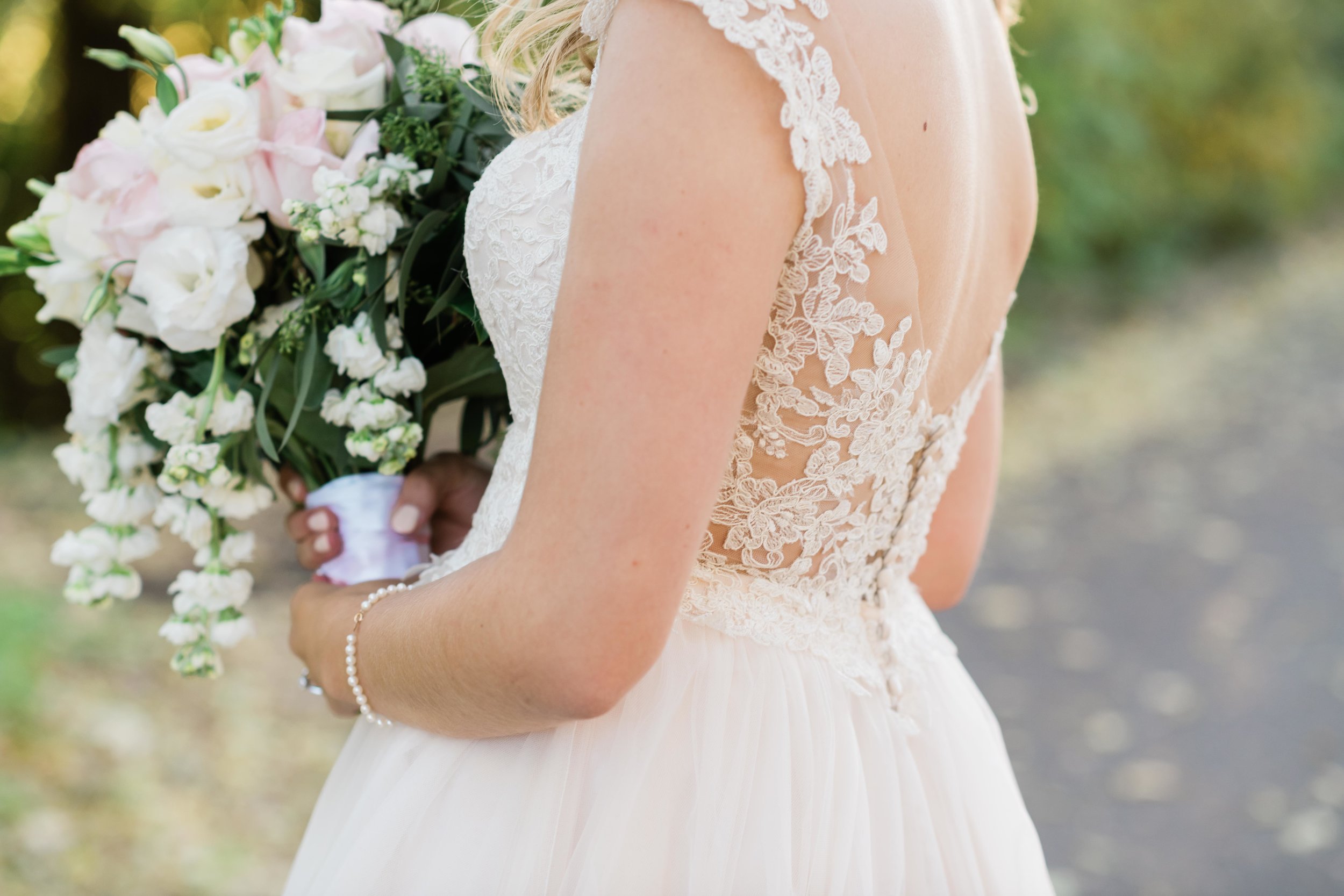 Back of bride's dress as she holds her bouquet