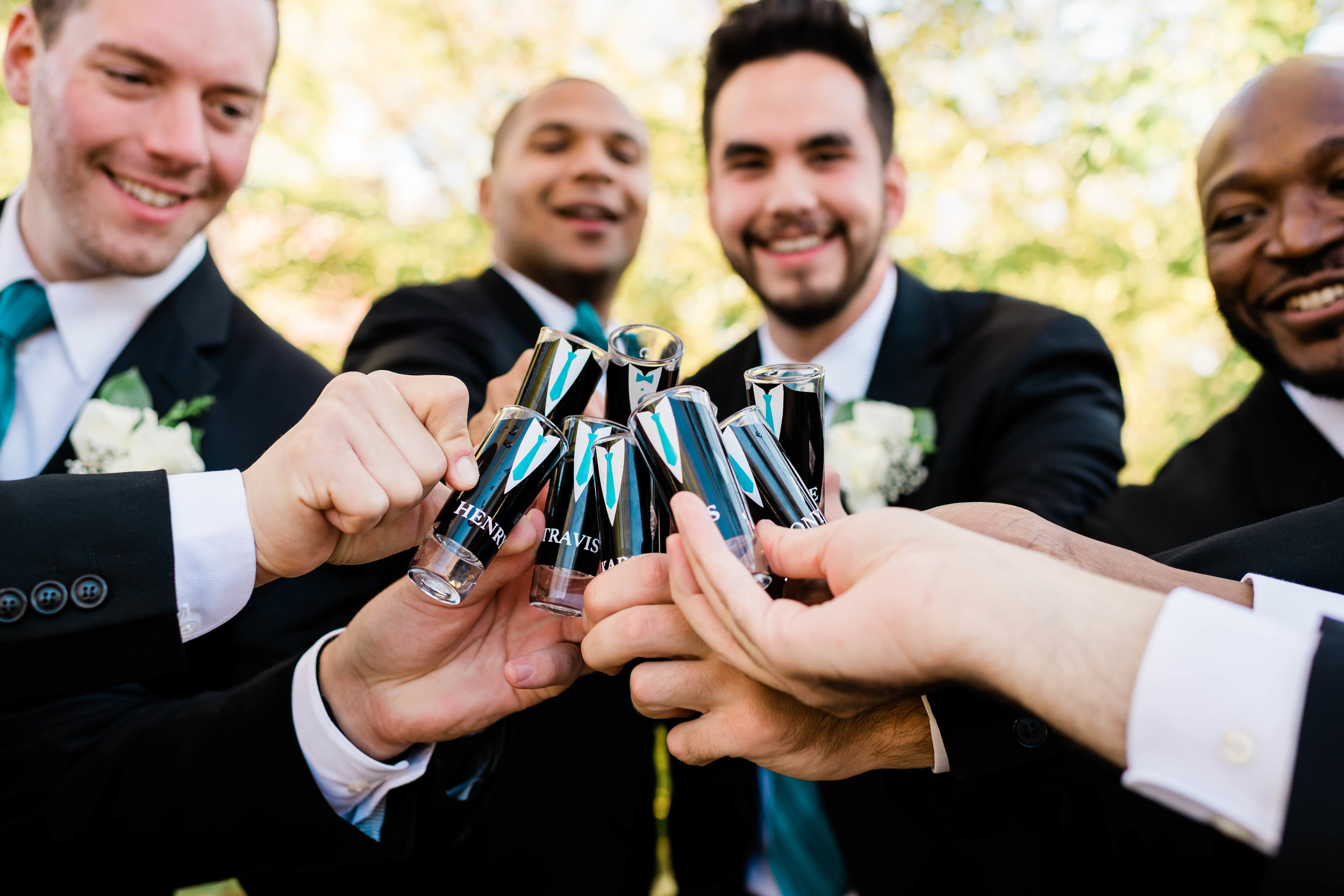 Groom and groomsmen raise their personalized shot glasses