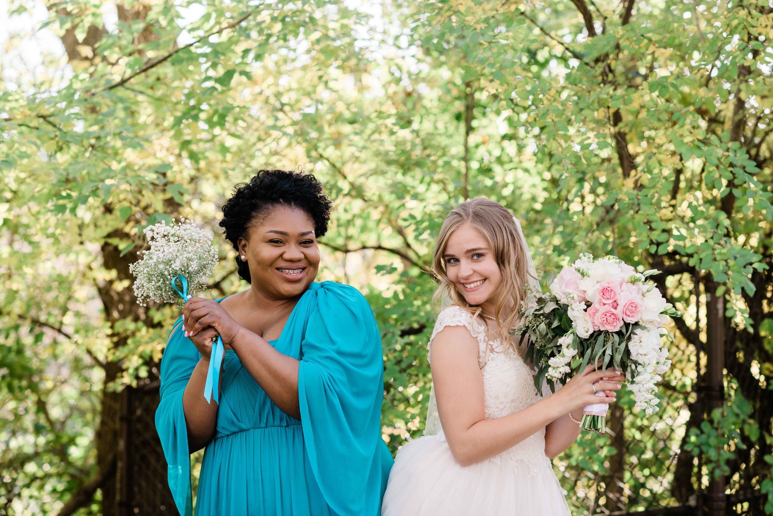 Bride and bridesmaid bump hips as they hold their bouquets