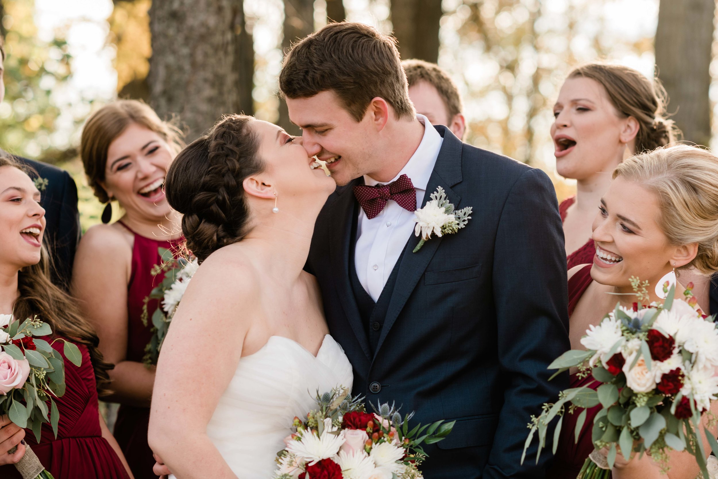 Bride and groom kiss as wedding party cheers them on