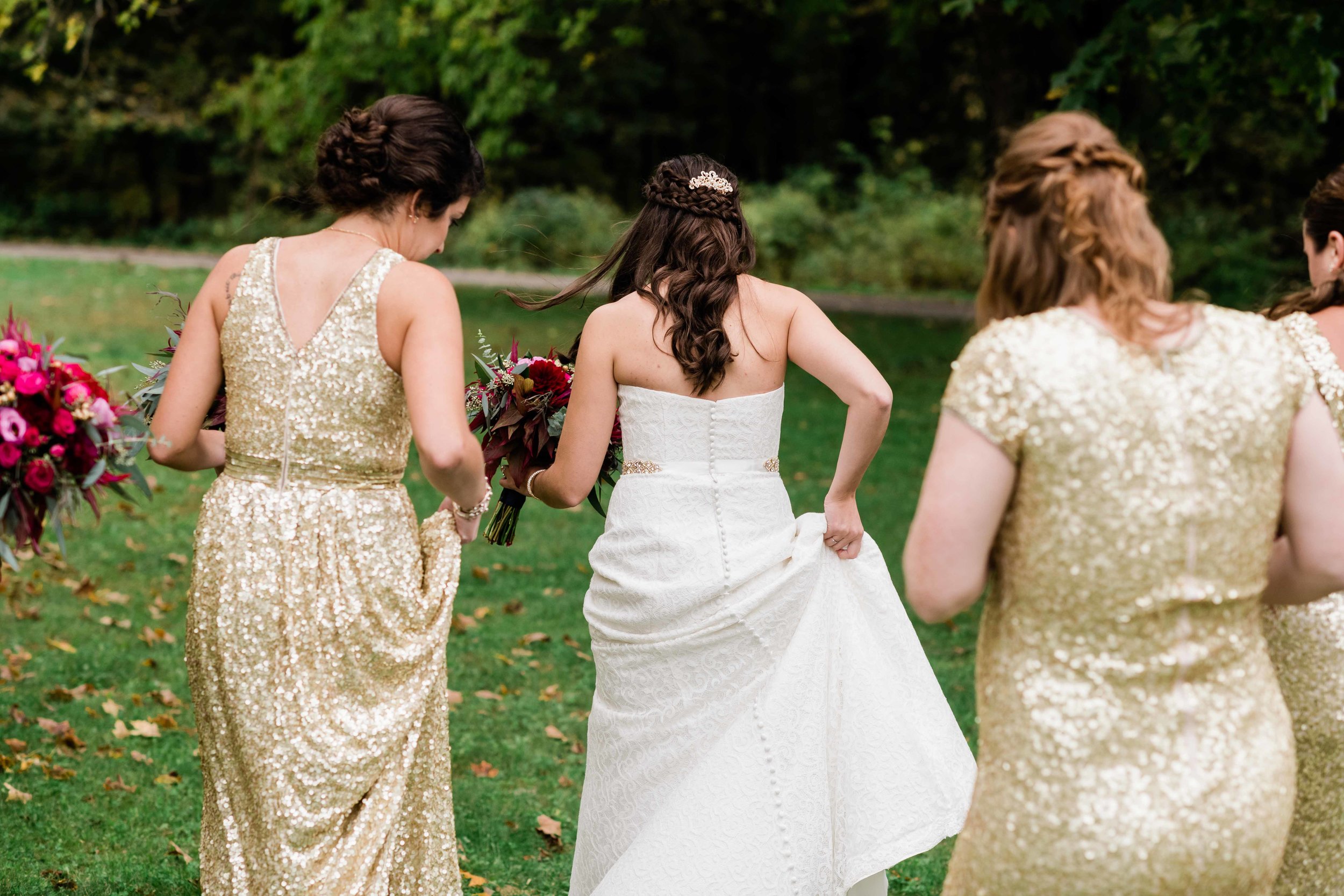 Bride and bridesmaids walking through grass