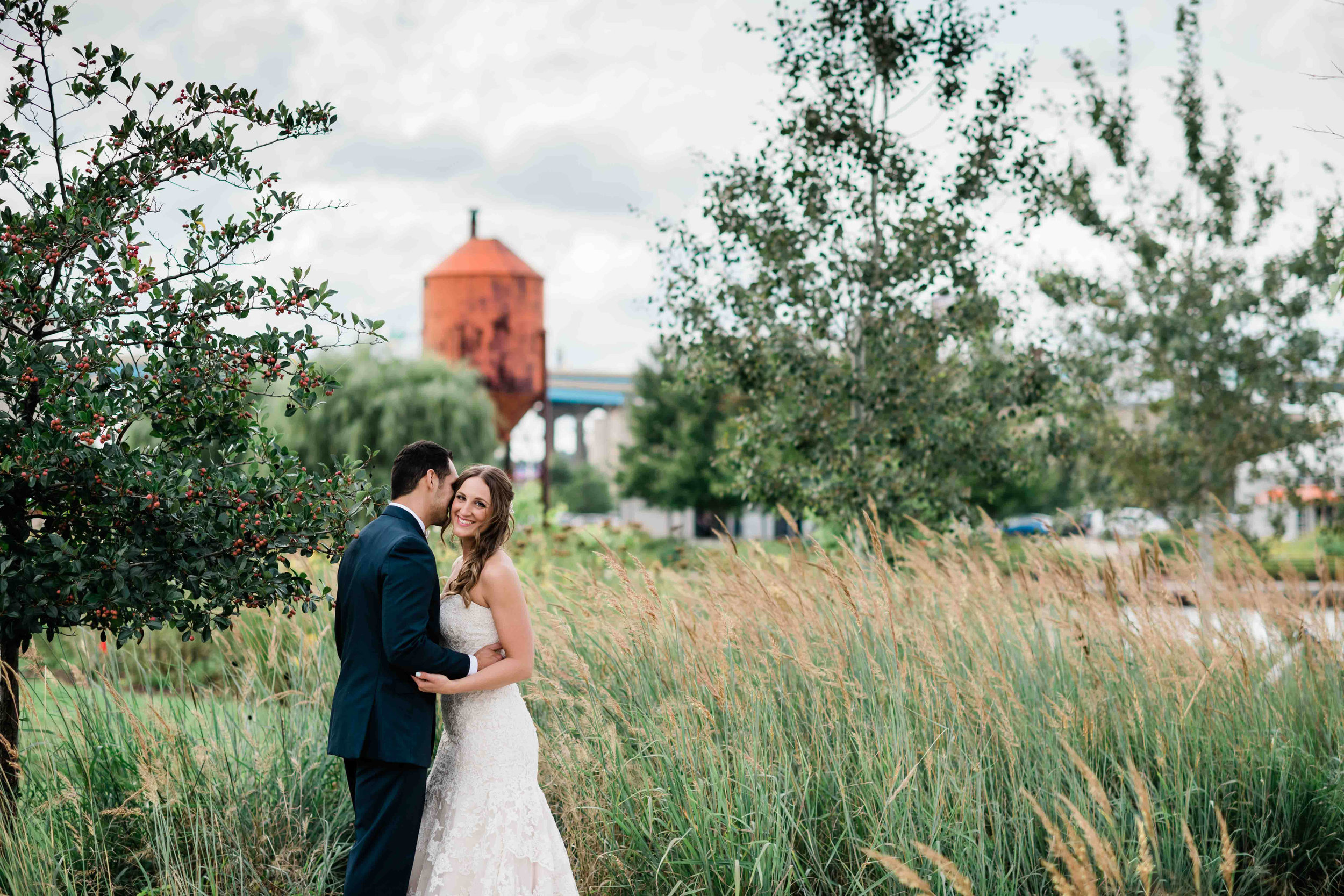 Bride smiling as groom whispers in her ear