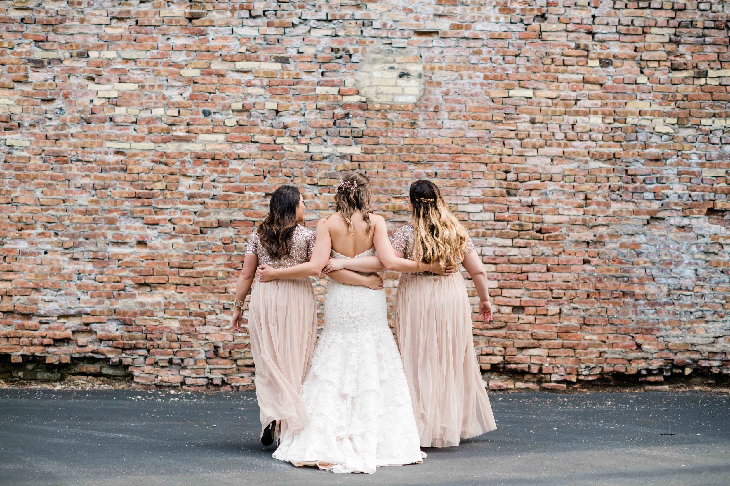 Bride and bridesmaids walk with arms around each other