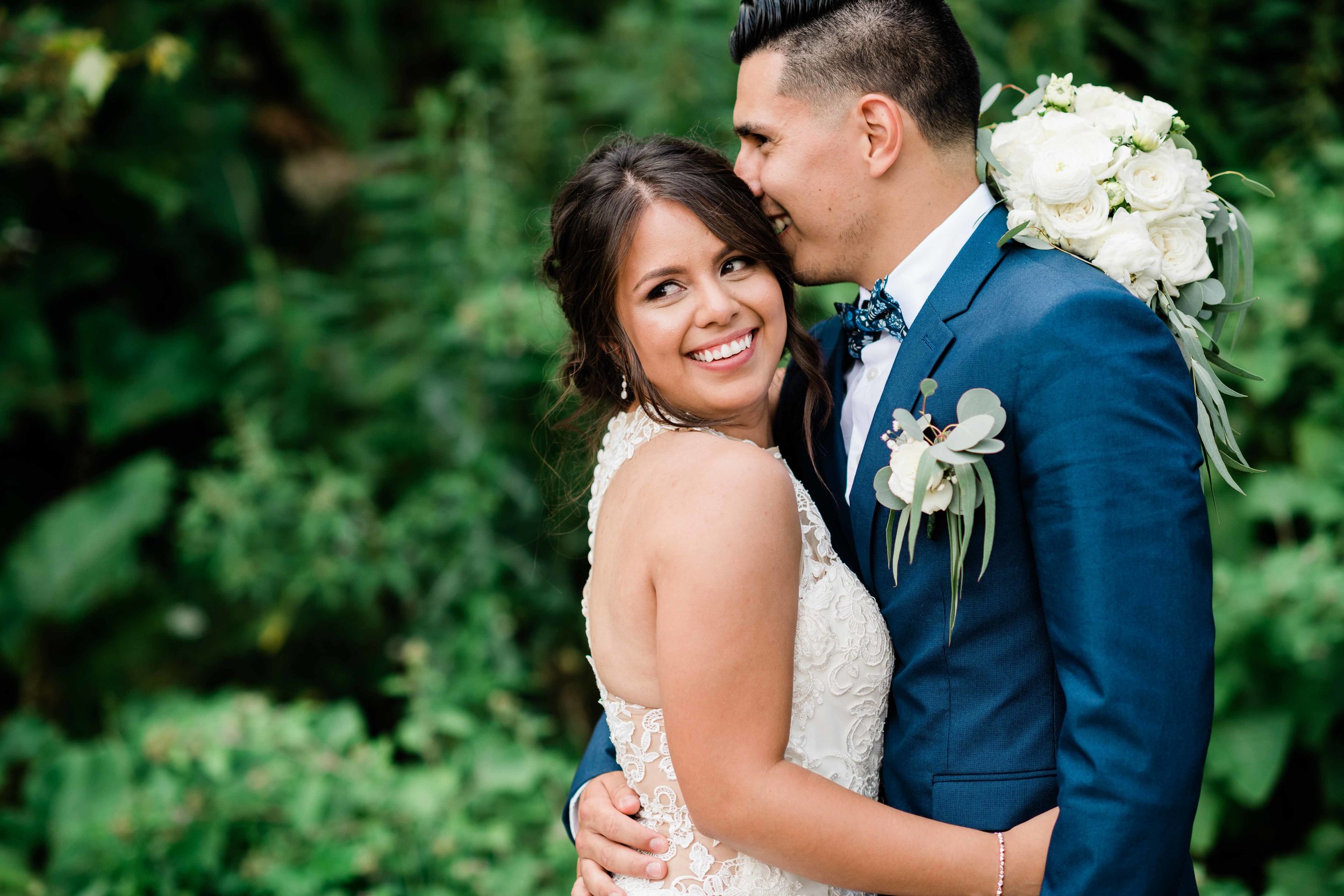 Groom kisses bride's head as she smiles