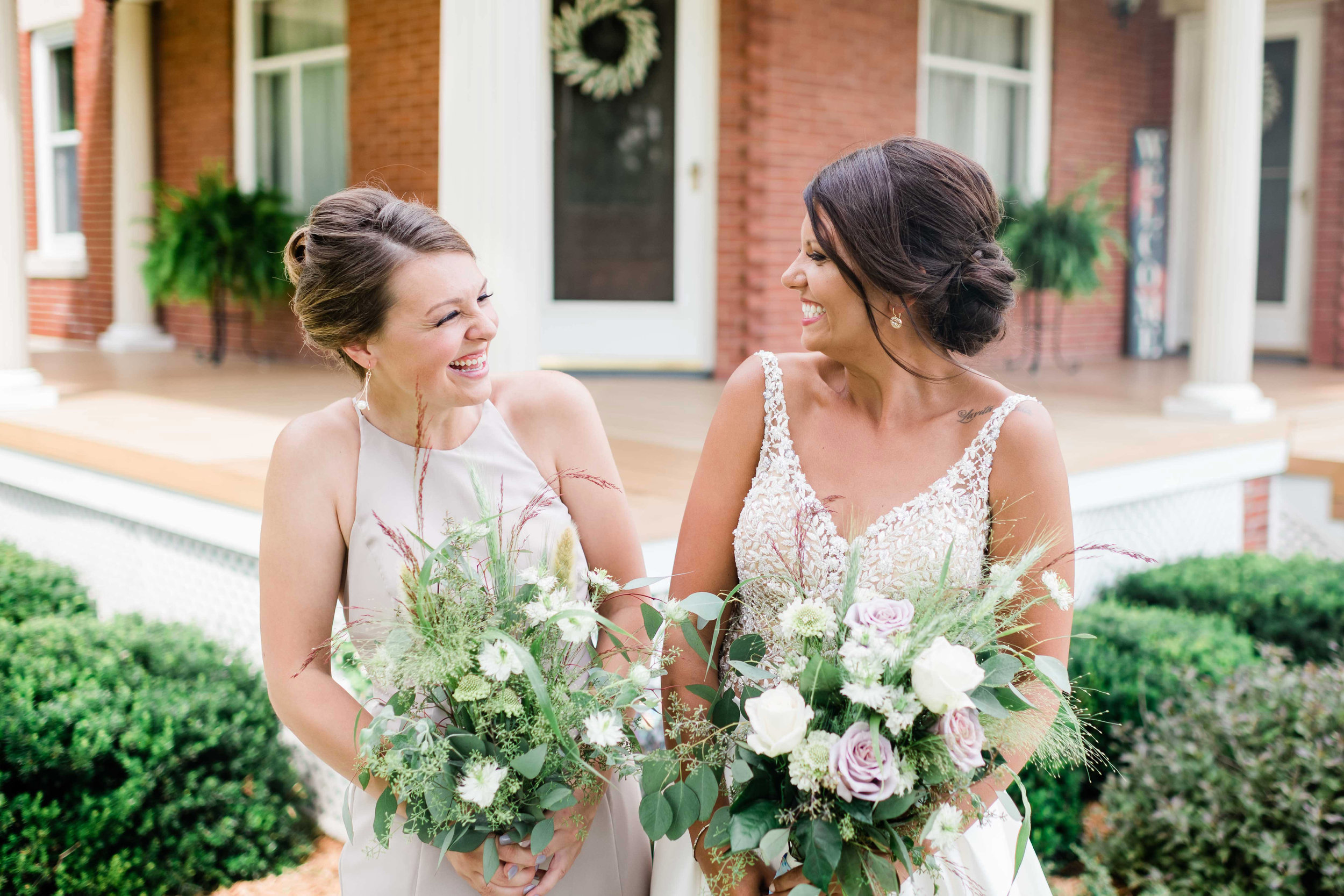 Bride and bridesmaid look at each other and laugh