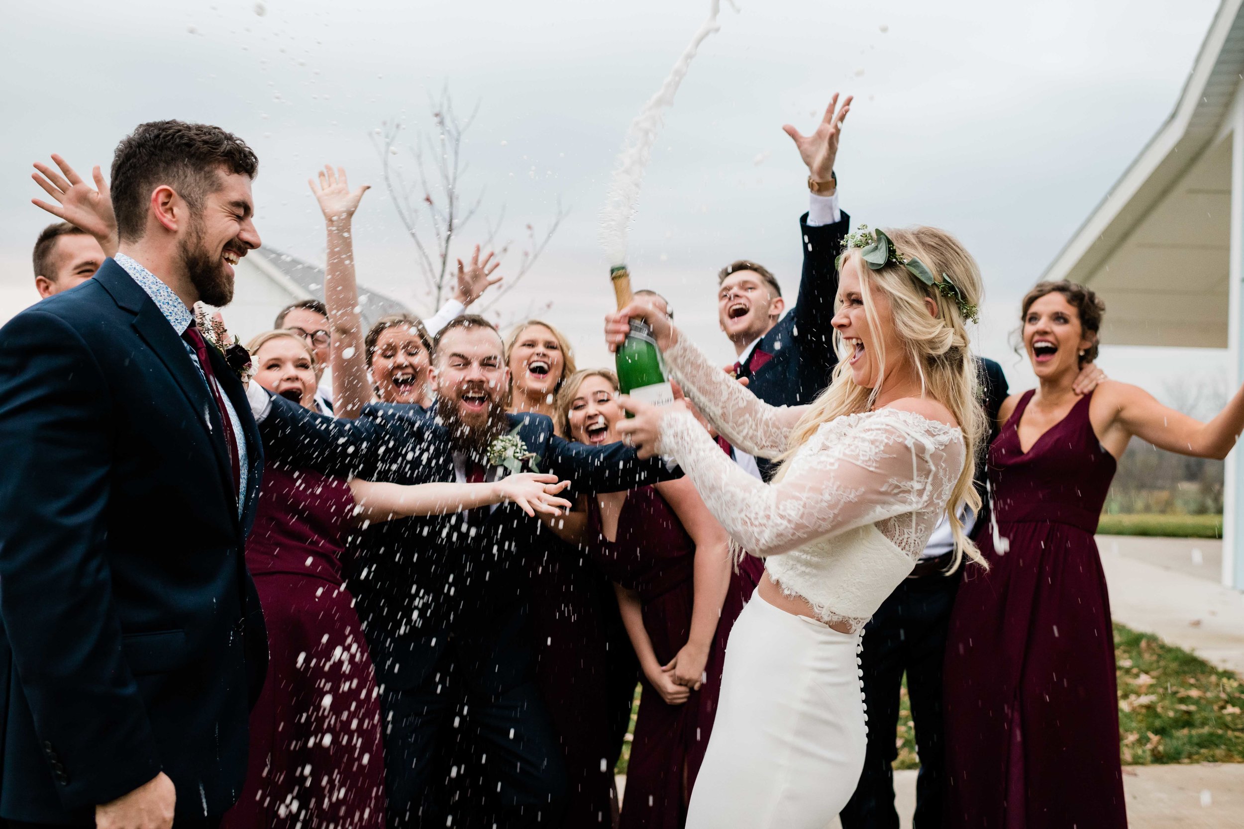 Bride opens champagne and it sprays all over wedding party