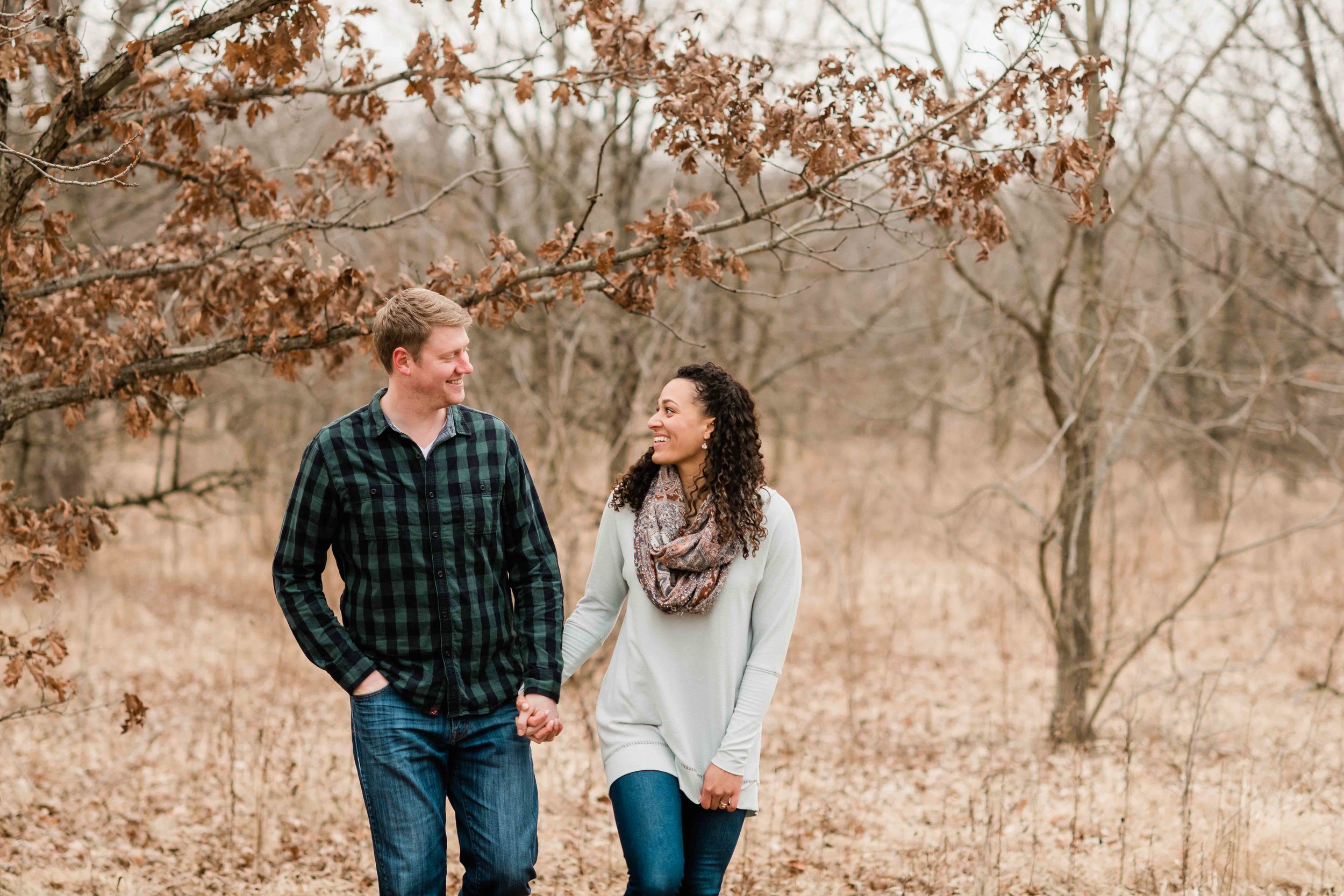 Engaged couple walking in a field before winter