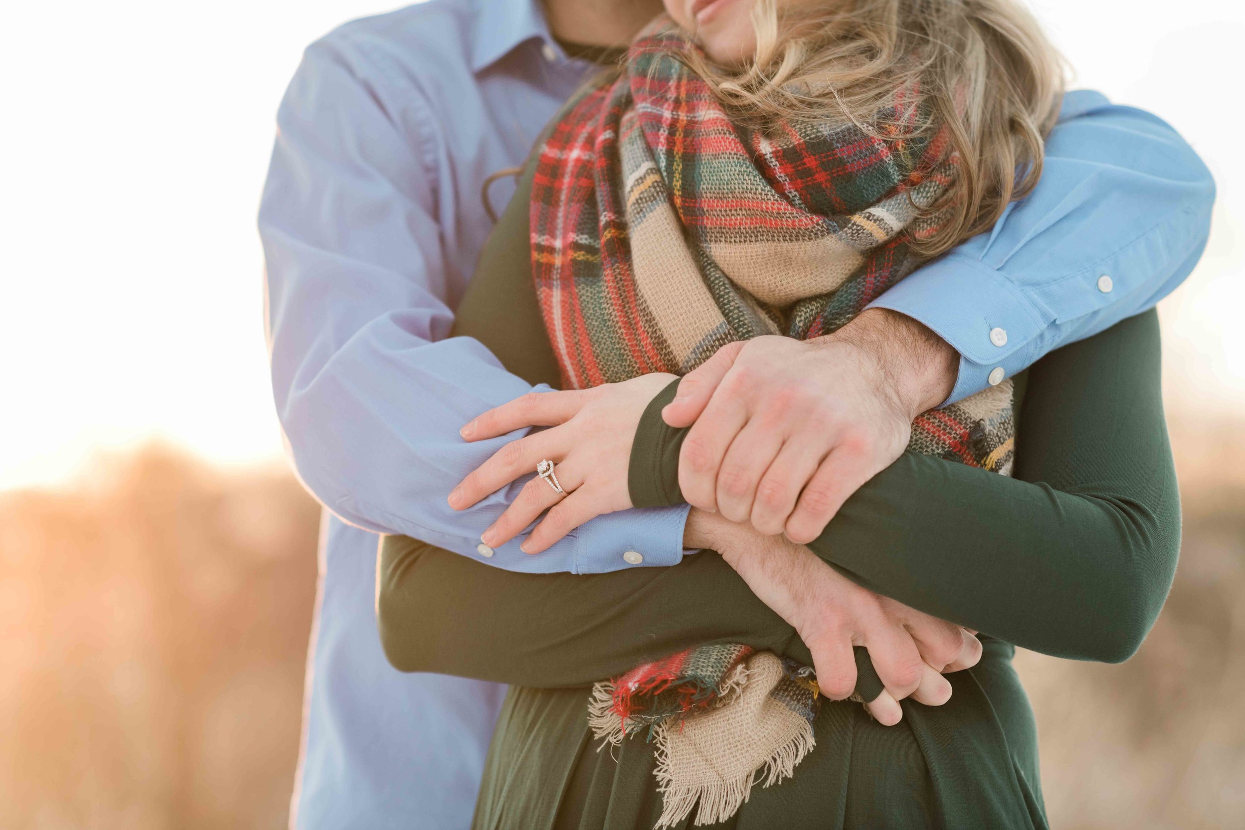Man wraps his arms around his fiancé to warm her up