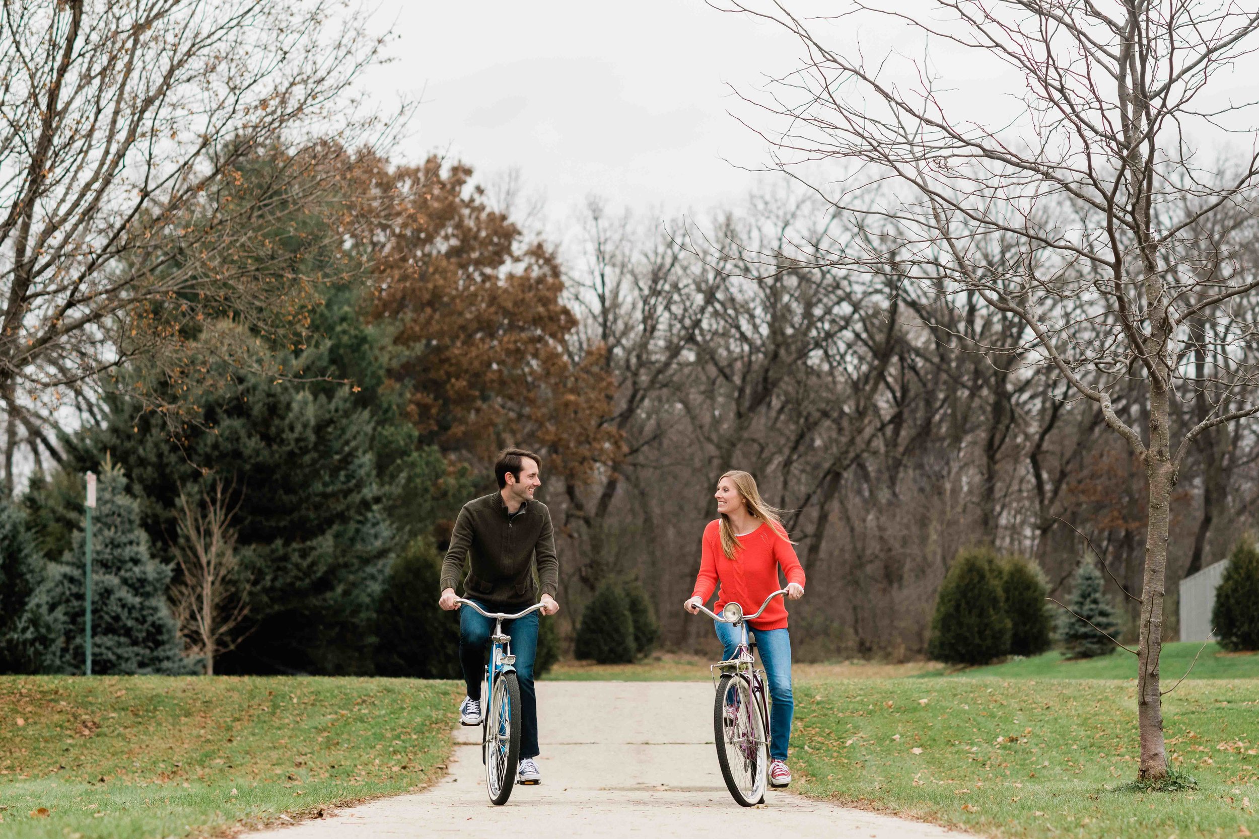 Engaged couple looks at each other as they ride bikes