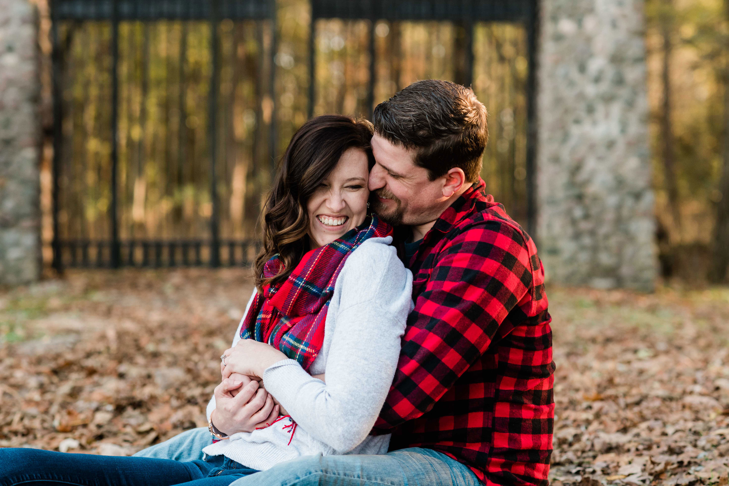 Engaged couple snuggling in the leaves outside