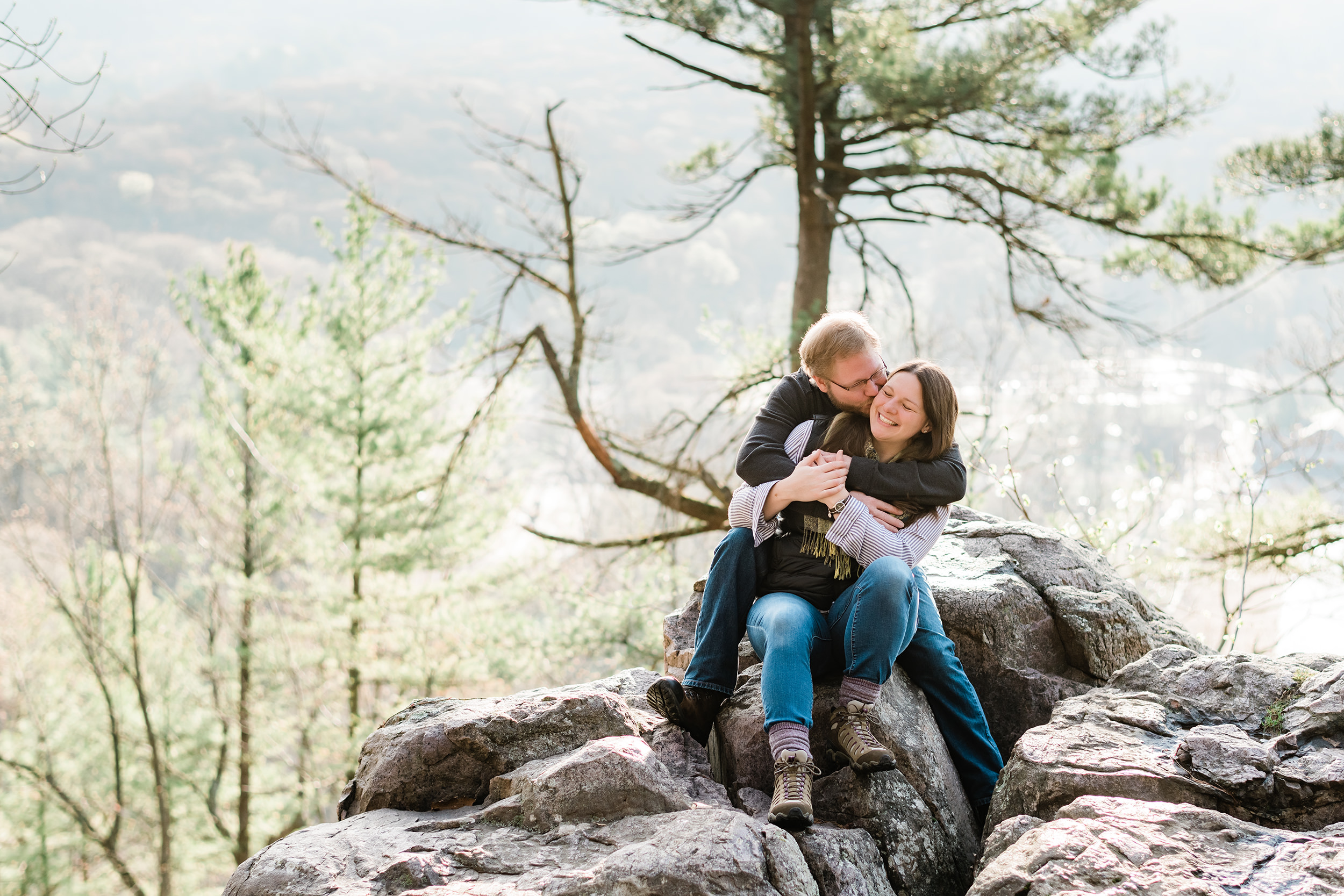 Engaged couple snuggling on a pile of rocks