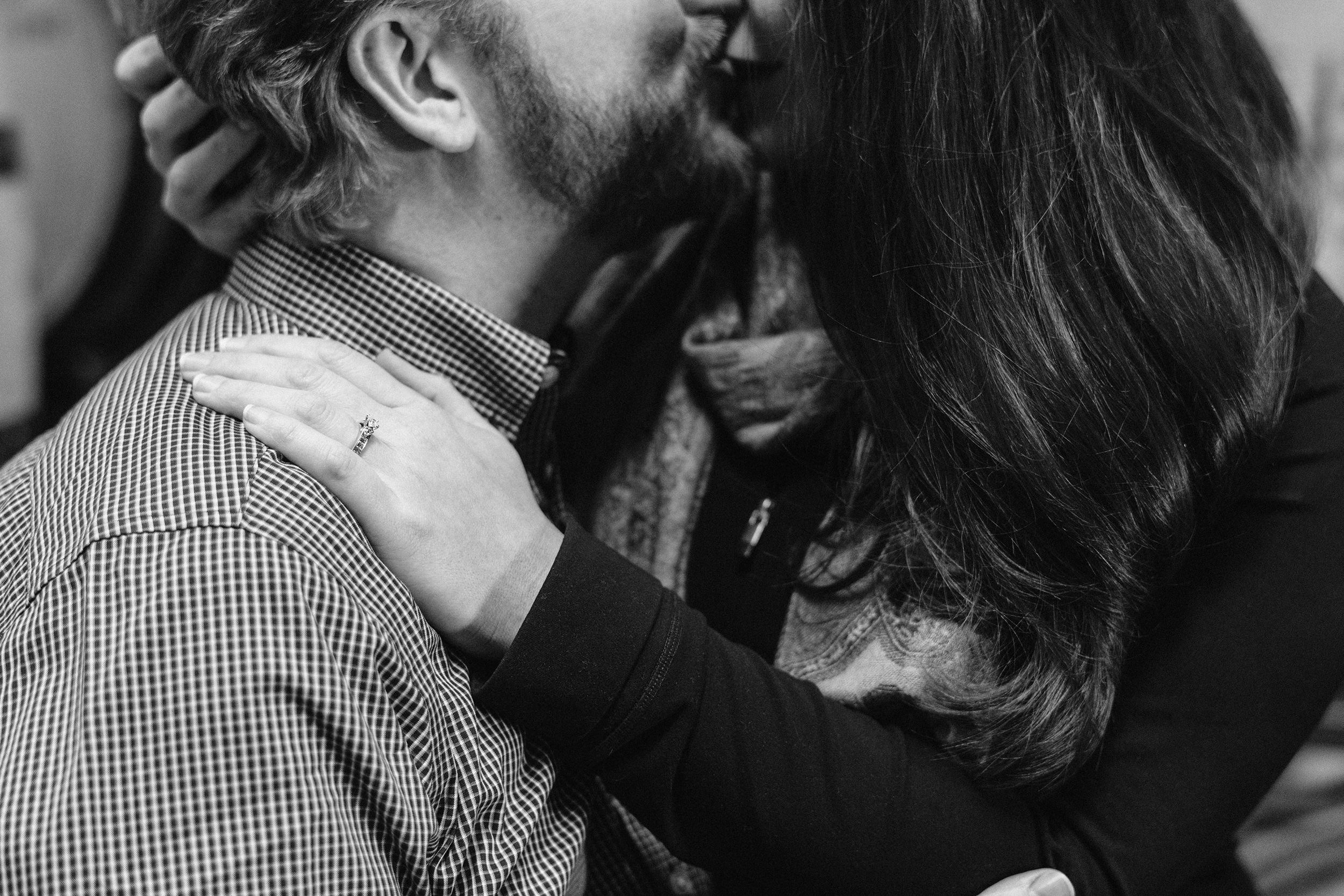 Woman rests her hand on fiancé's shoulder showing her engagement ring