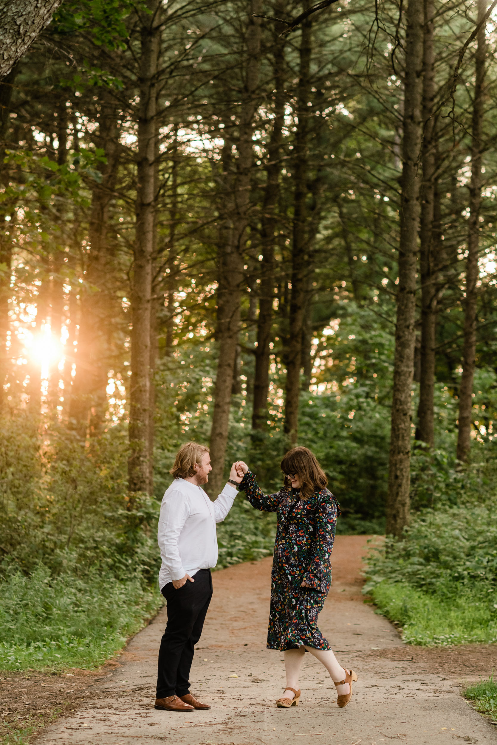 Man twirling his fiancé in the woods