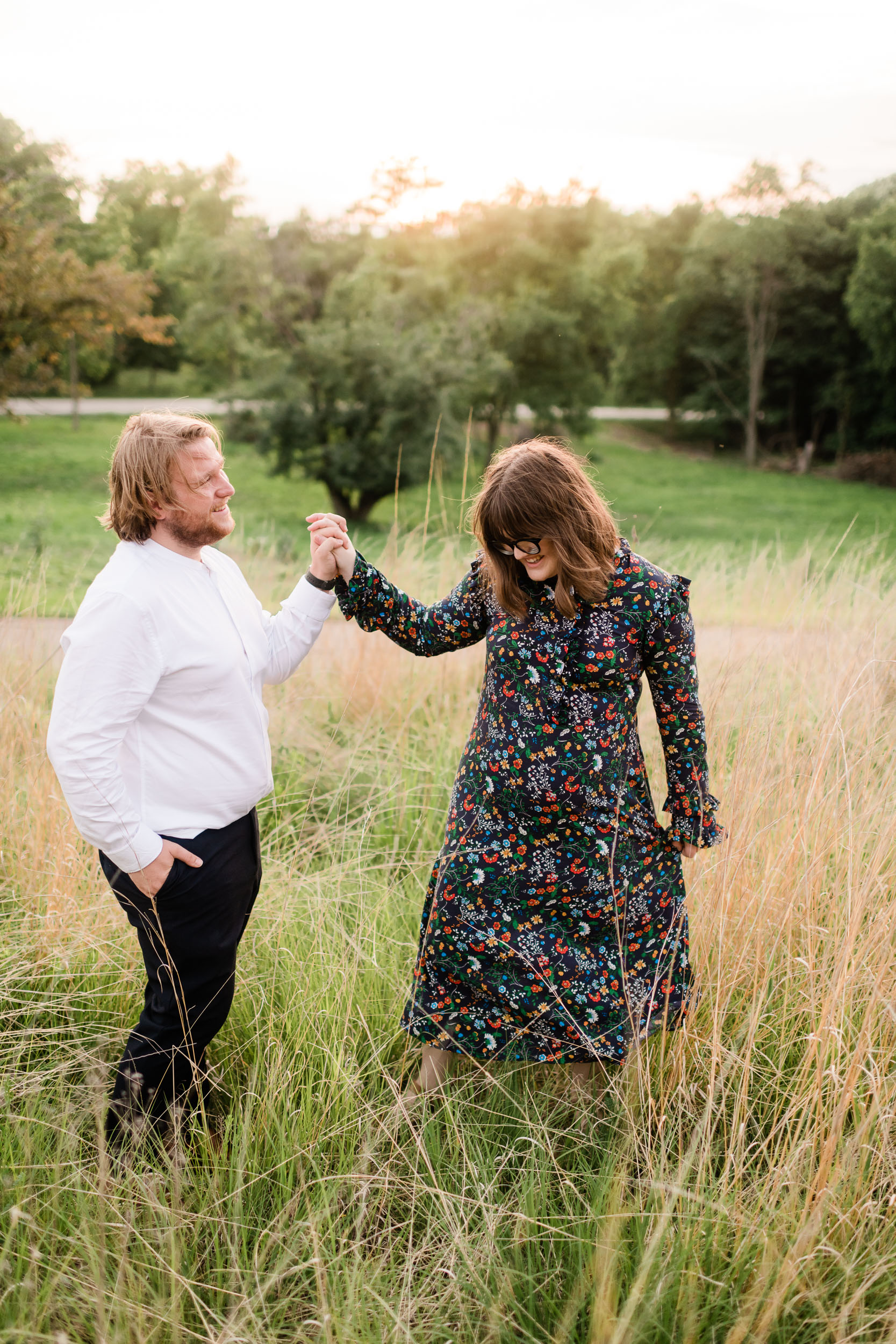 Engaged couple twirling in a field