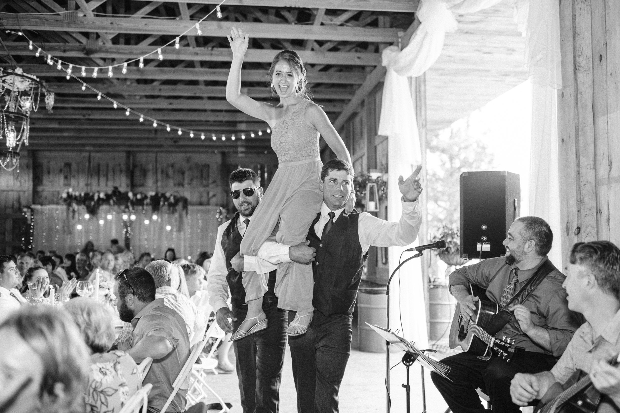 Groomsmen carrying bridesmaid into reception