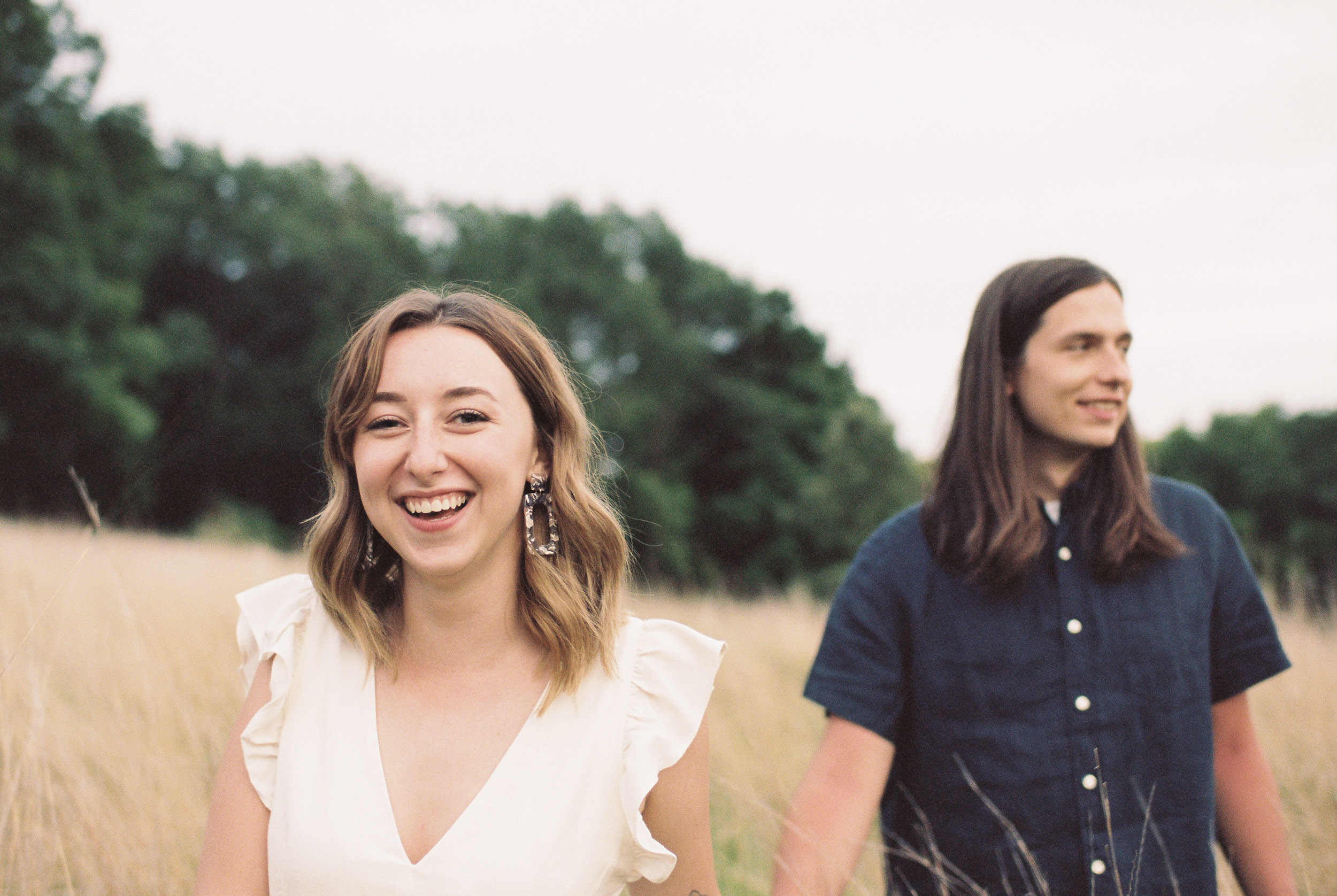 Woman leading her fiancé through a field