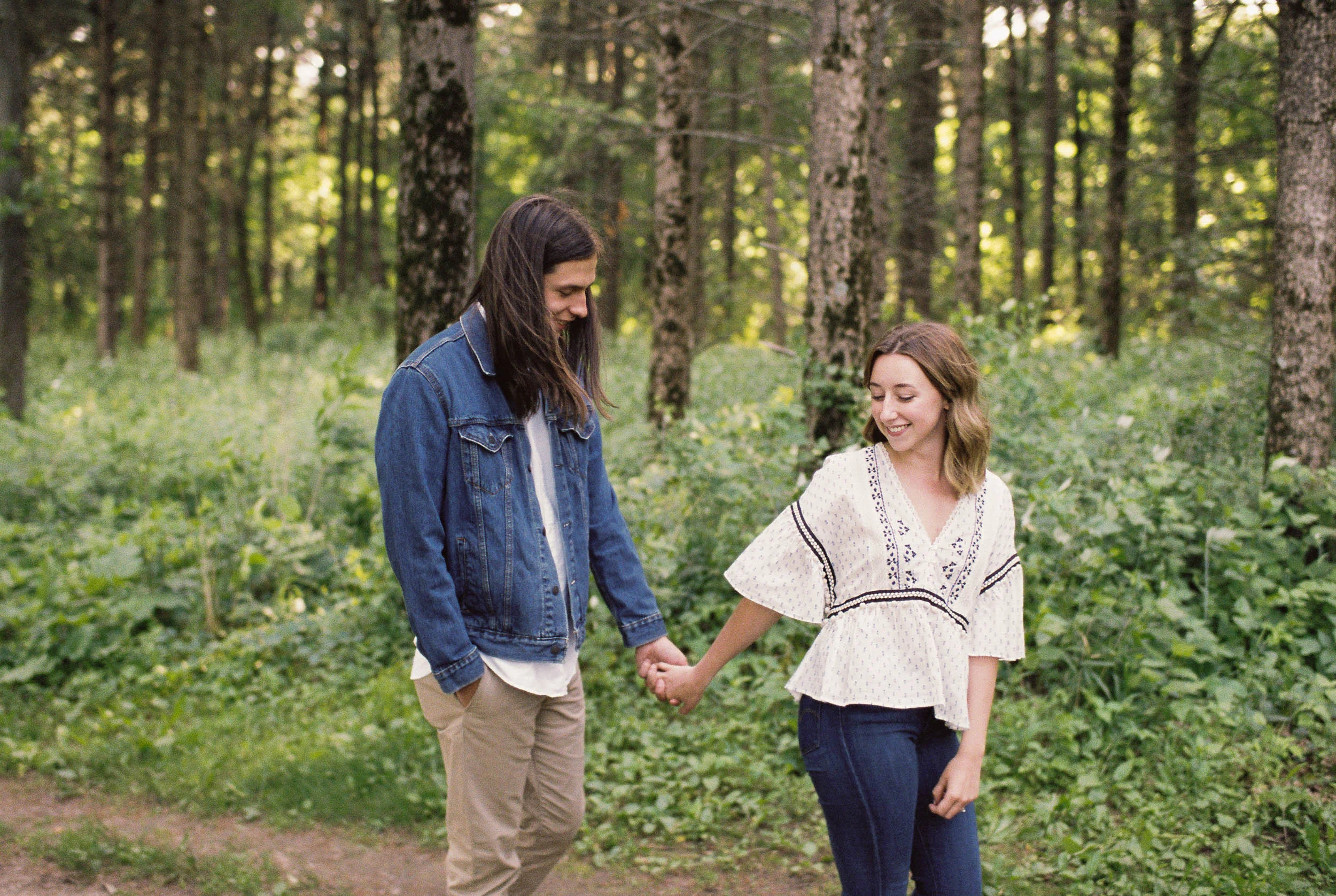 Engaged couple holding hands in the woods