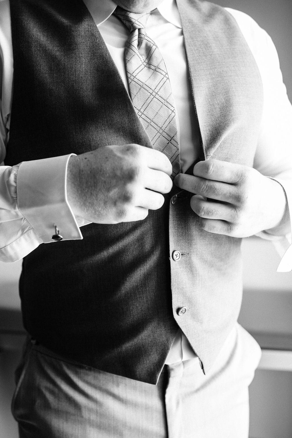 Groom buttoning his vest