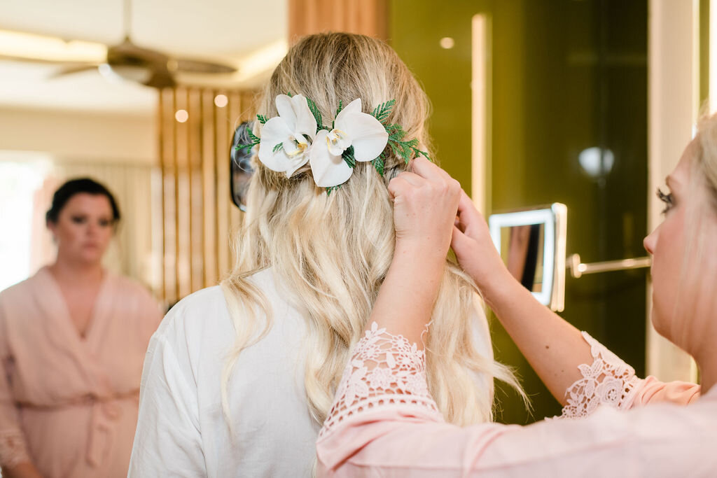 Bridesmaid putting flowers in bride's hair