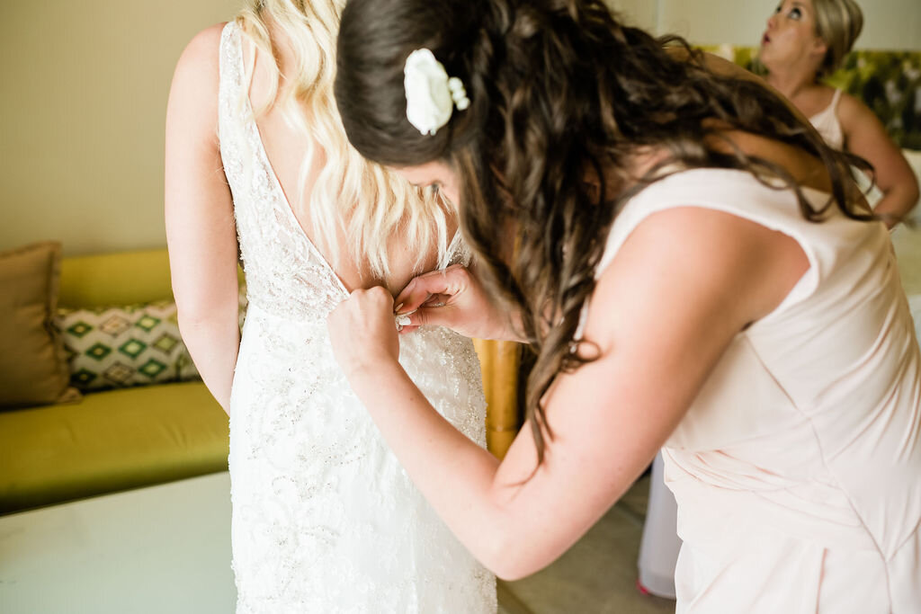 Bridesmaid fastening bridal gown