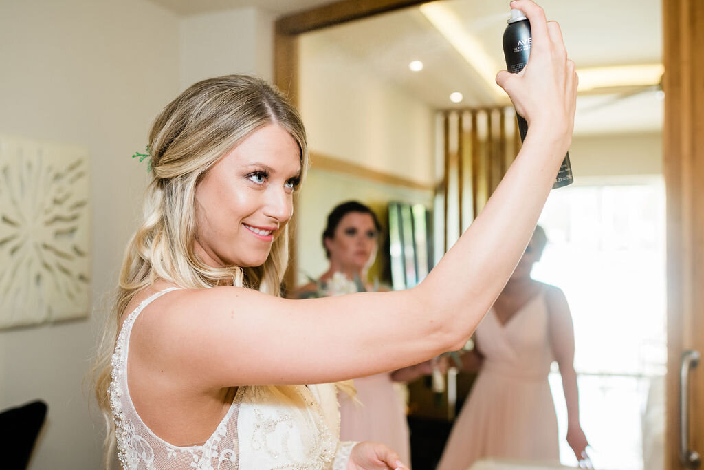 Bride spraying hairspray on her hair