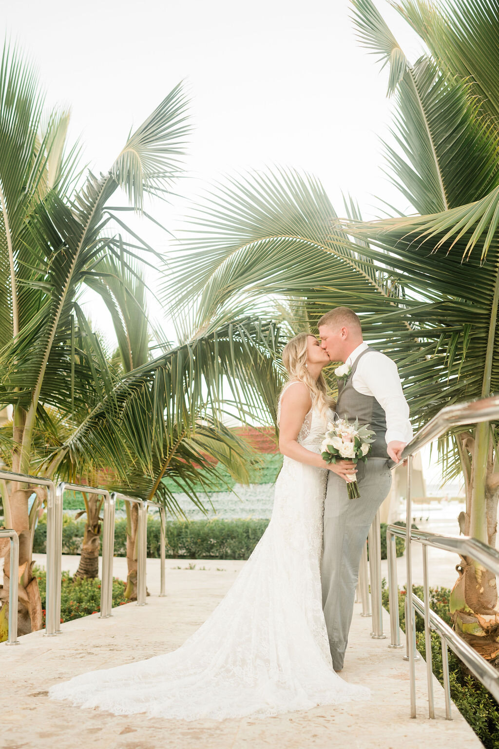 Bride and groom kissing under a palm tree