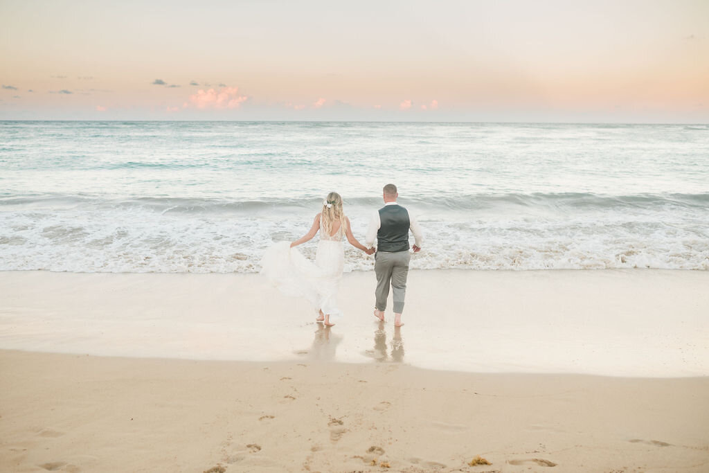 Bride and groom running into the ocean