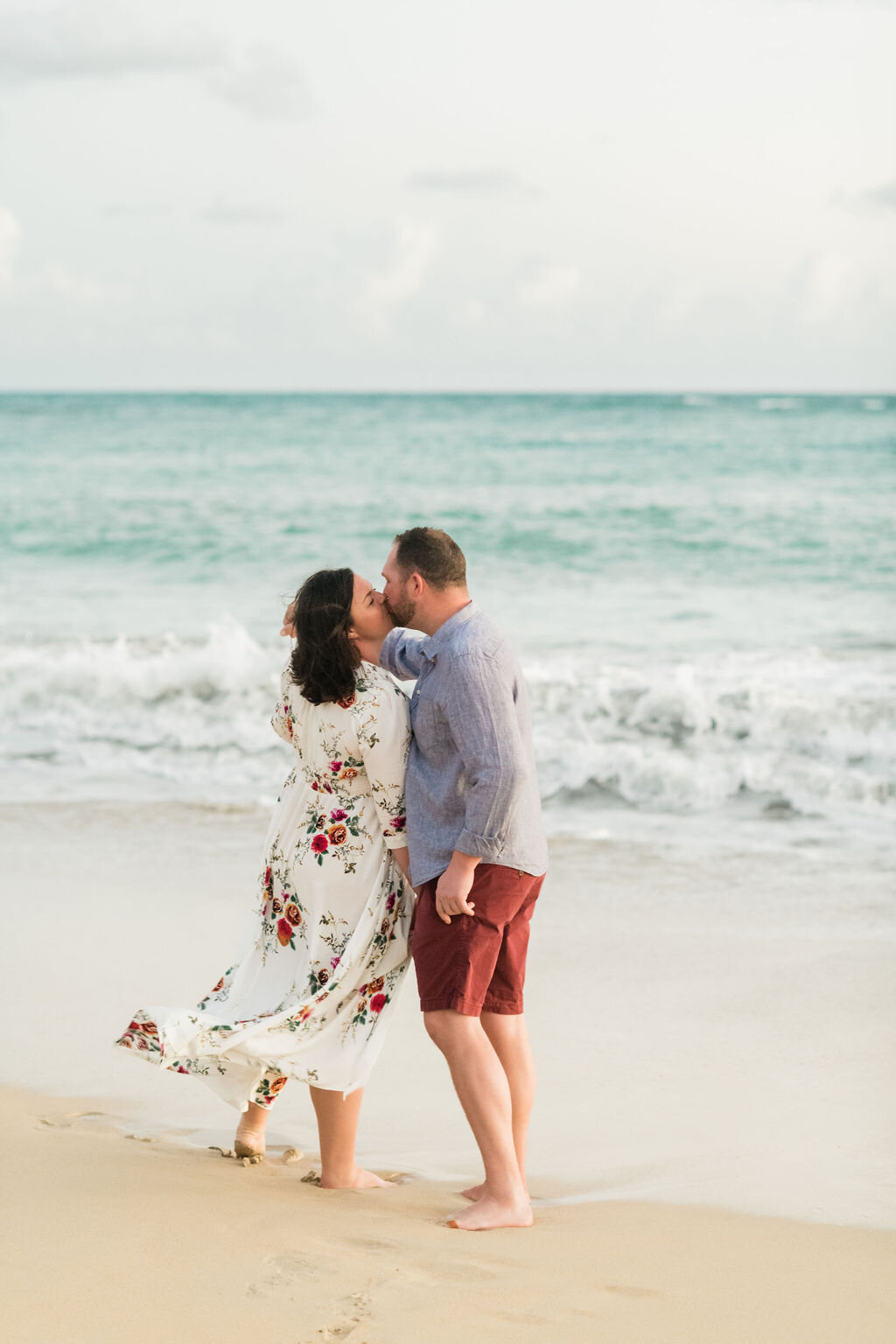 Engaged couple kissing by the ocean