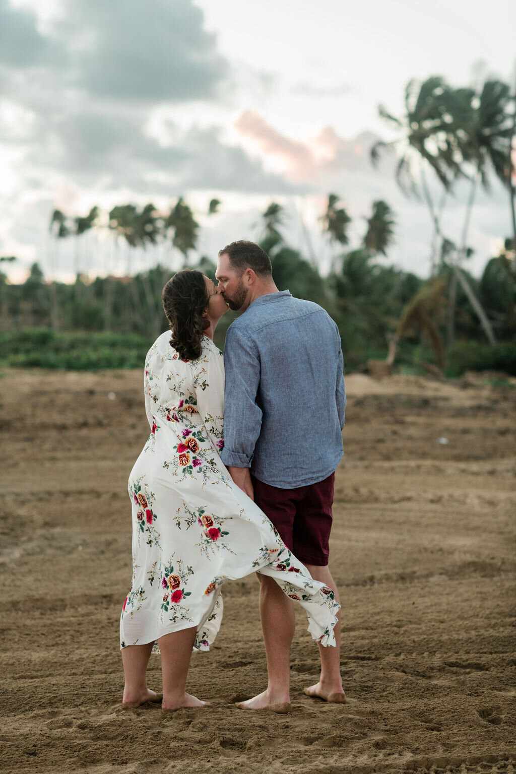 Engaged couple kissing in front of palm trees