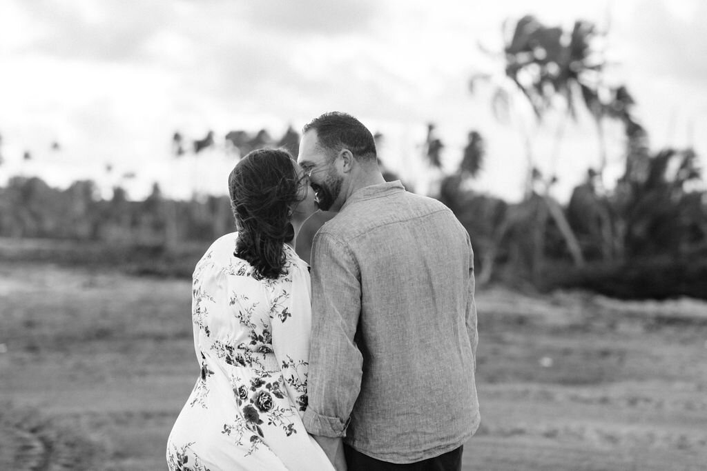 Engaged couple kissing in front of palm trees