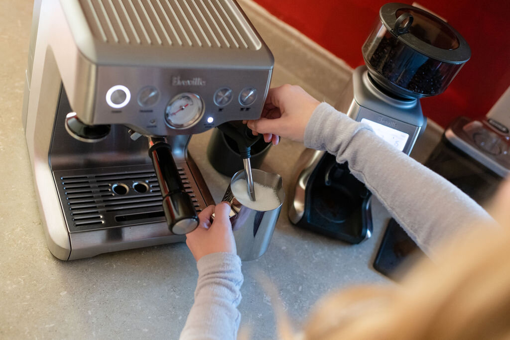 Woman foaming milk for a latte