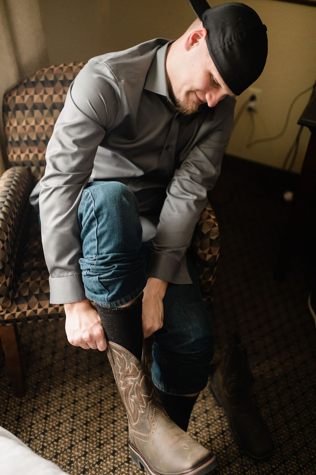 Groom putting cowboy boots on