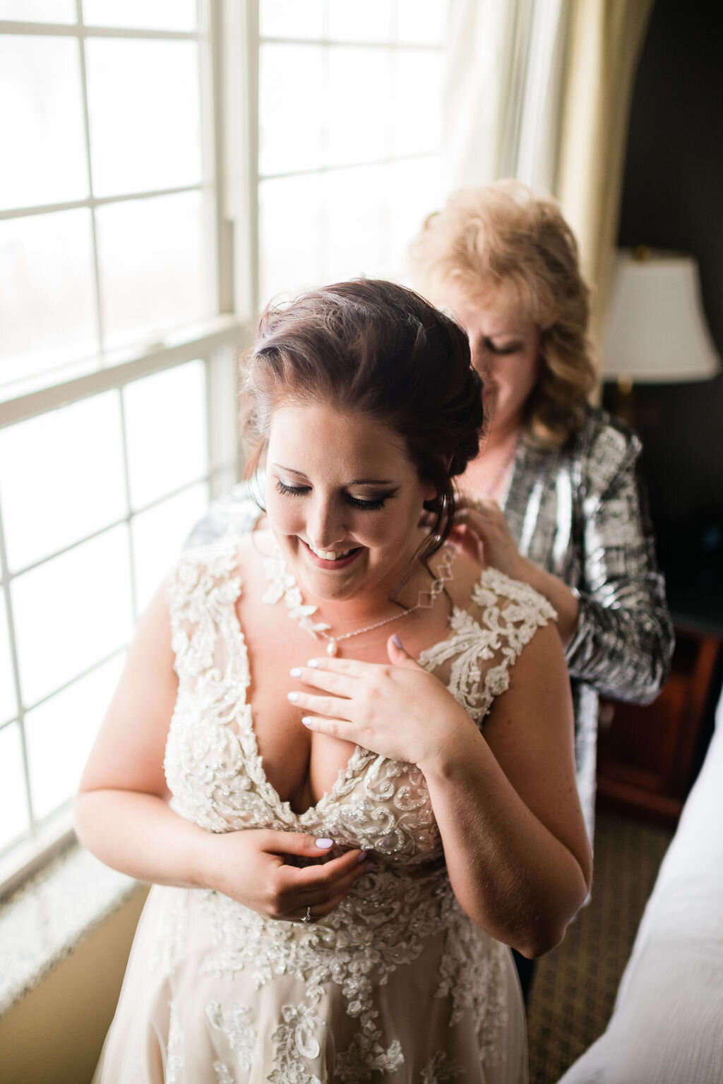 Mother of the bride putting on the bride's necklace