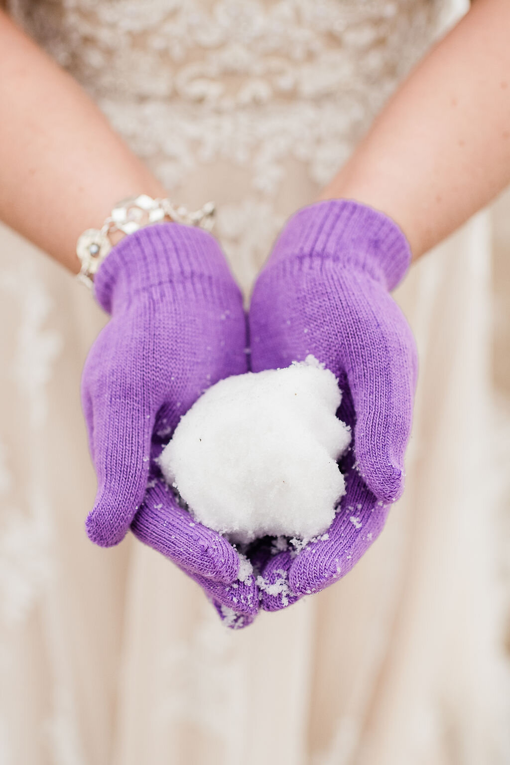 Bride wearing purple gloves and holding a snowball in her hands