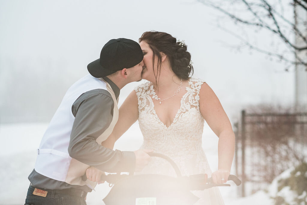 Bride and groom kissing on a snowmobile