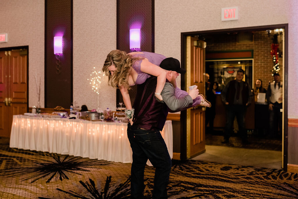 Groomsman carrying bridesmaid into reception