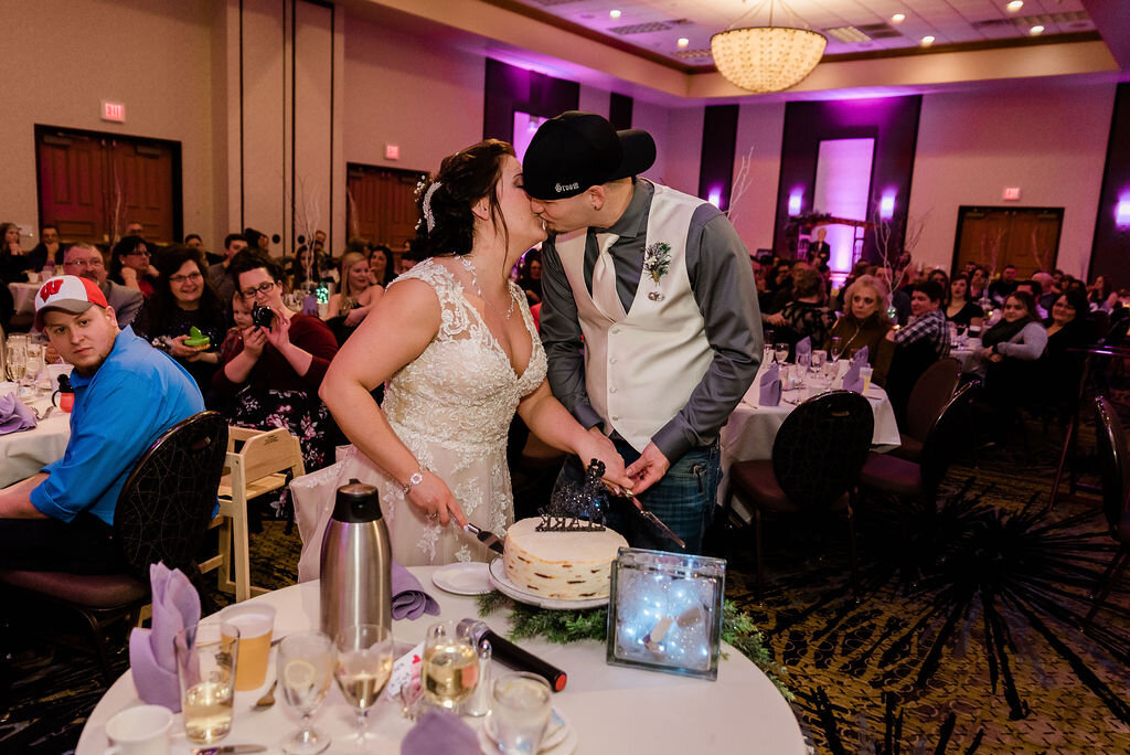 Bride and groom kissing by the cake